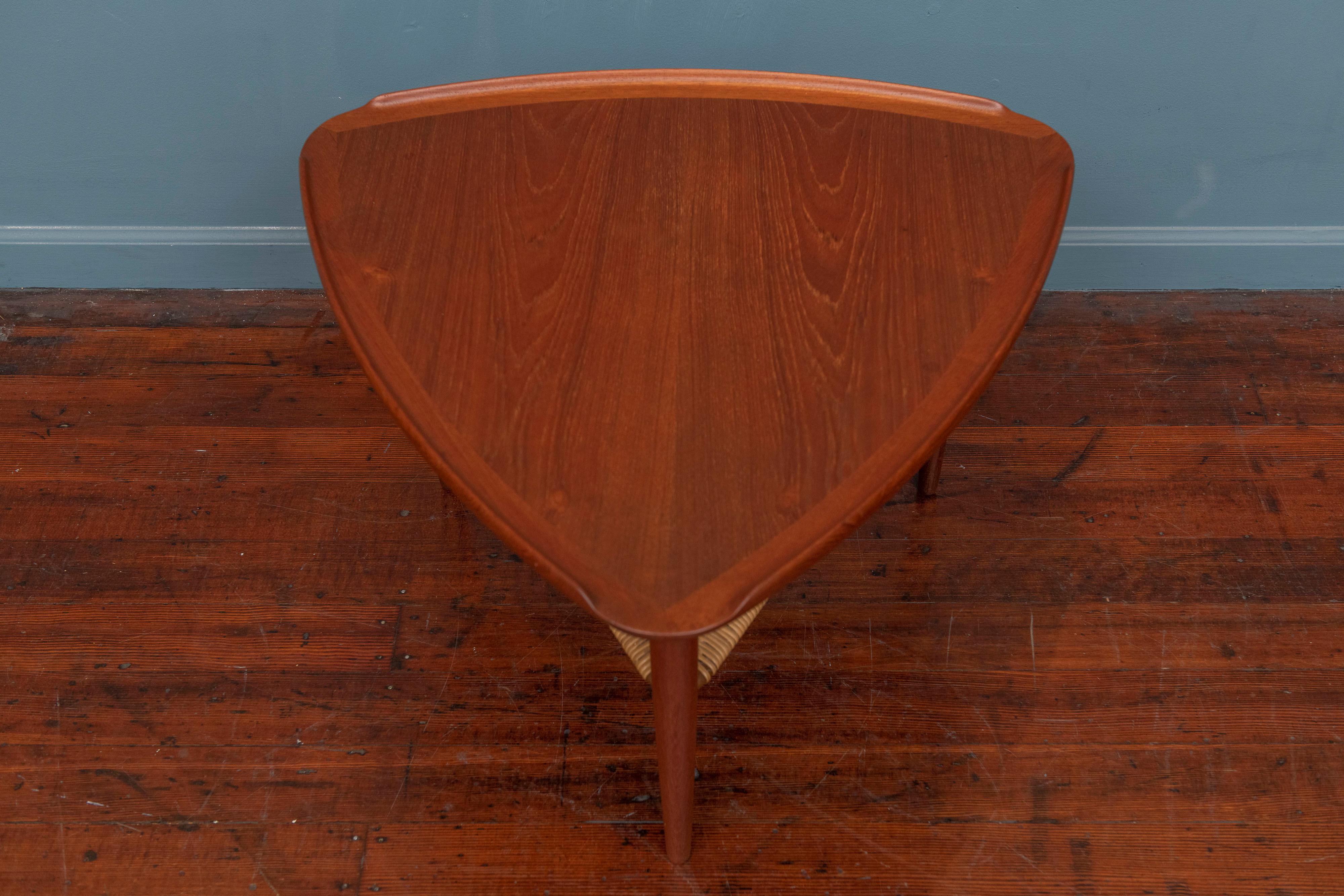 Poul Jensen triangle form teak and cane side table for Selig, Denmark. High quality construction and attention to detail with sculpted edges and a cane shelf, labeled.