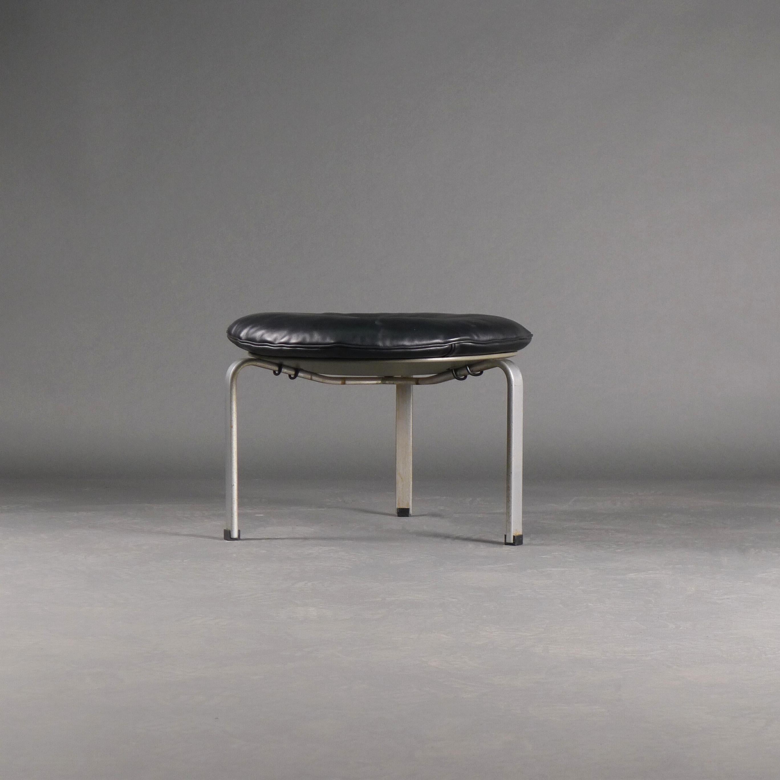 Circular PK33 stool, designed in 1958 by Poul Kjaerholm and manufactured by E Kold Christensen (bears their stamp).

Removable leather seat cushion with central button, grey lacquered plywood circular seat and steel legs with black plastic