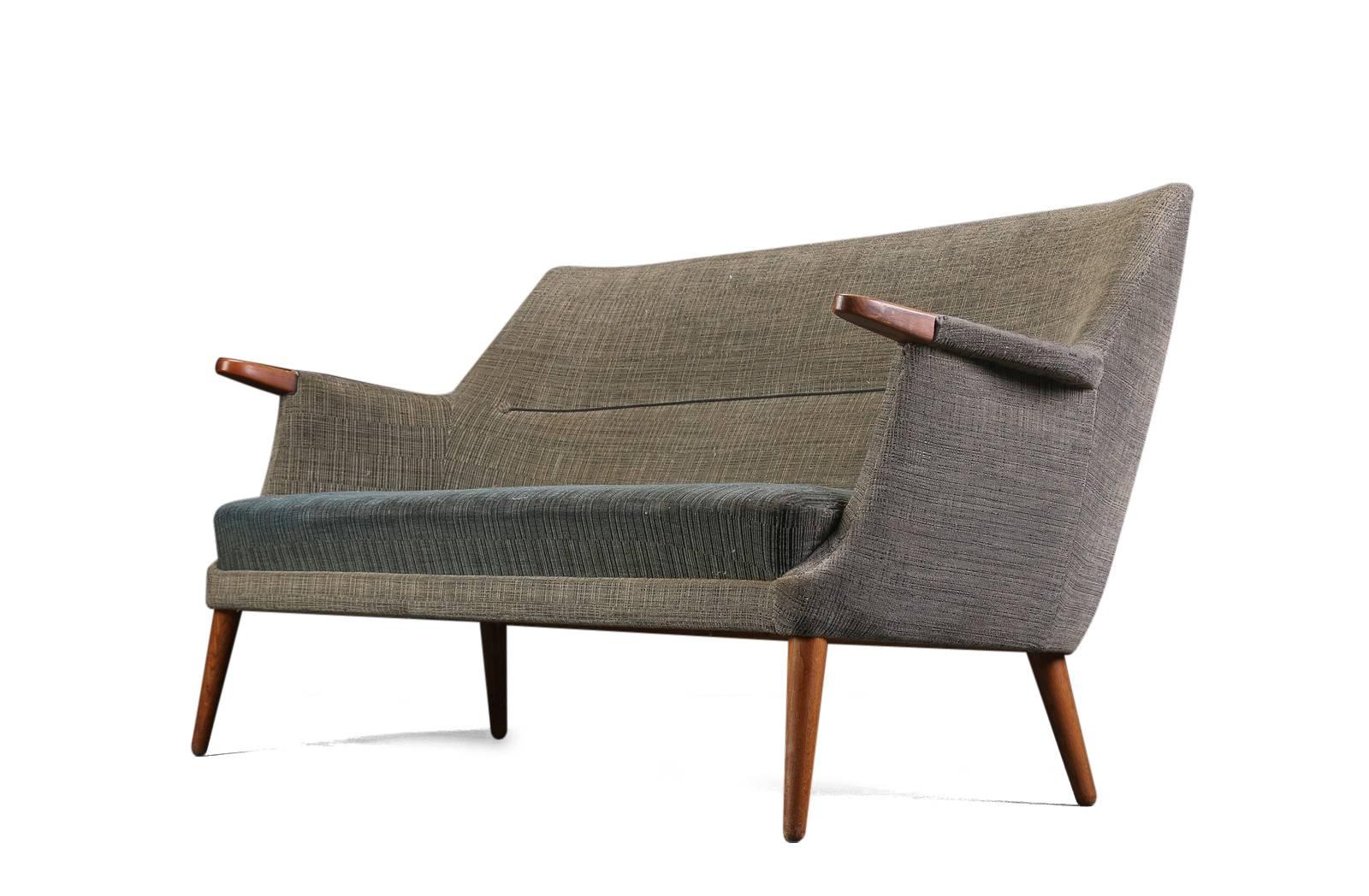 Poul M. Jessen three-seat upholstered sofa, upholstered with wool, round tapered oak legs; armrests with teak “nails”, 1960. 
Measures:  H 80, seat height approximately 40, L 170 cm. The upholstery has defects.