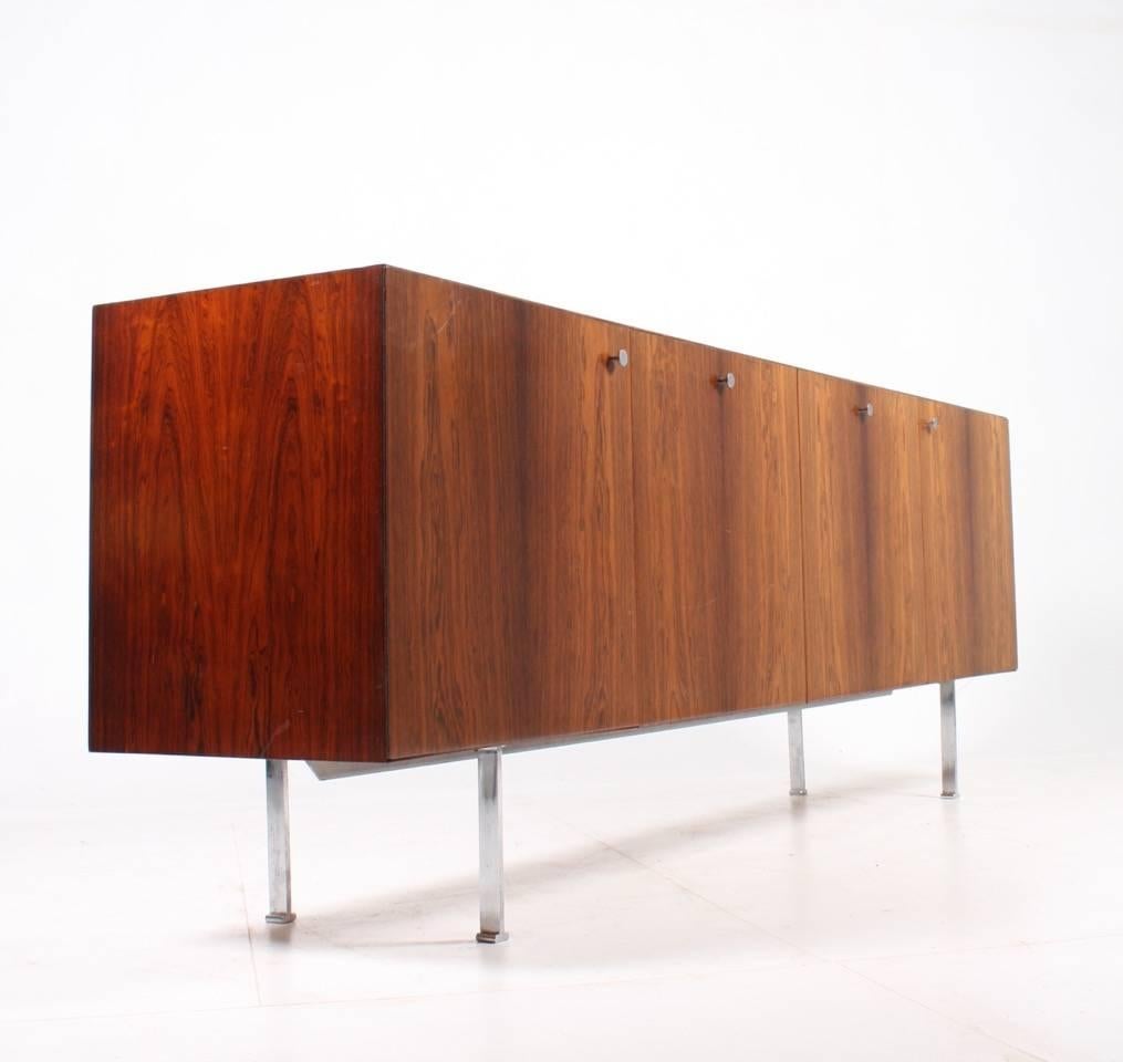 Great looking sideboard, front with four doors, legs and handles of chromed steel. All edges with diagonal cut in rosewood designed by Poul Nørreklit for Georg Petersens Møbelfabrik. Great original condition.