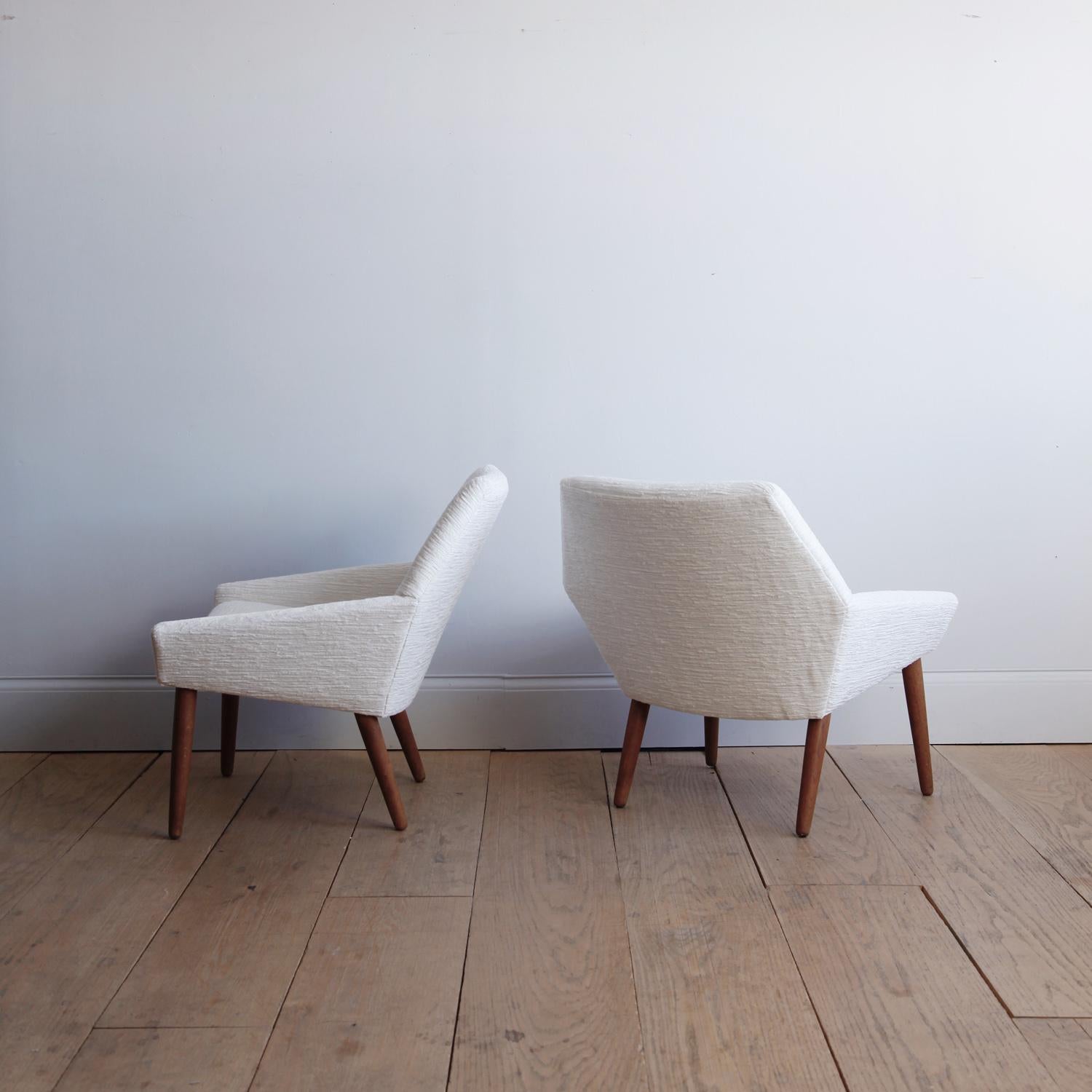 A pair of modern lounge chairs with a minimalist, planar design, recently reupholstered in a soft ivory chenille.
