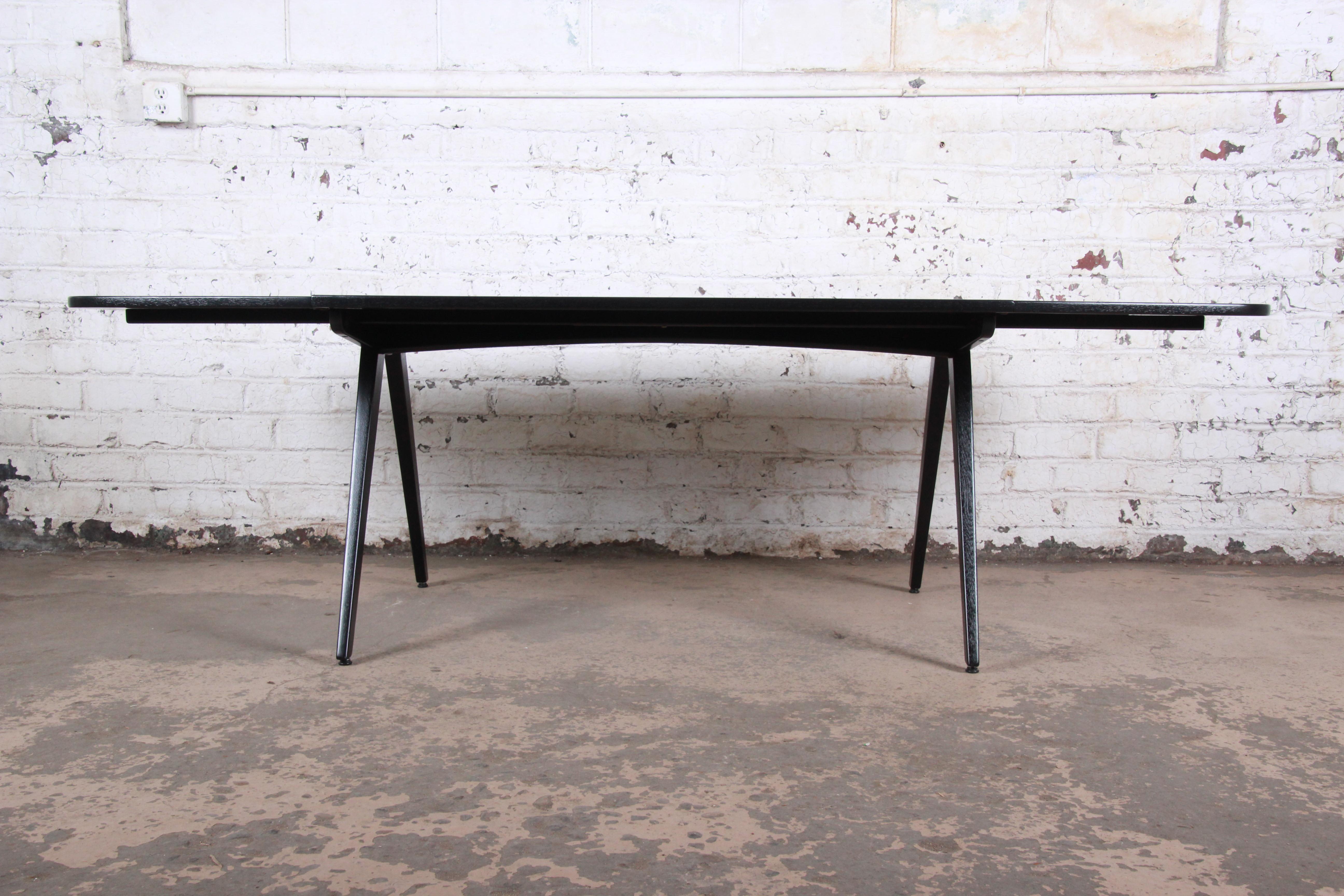 An outstanding Danish modern ebonized teak boat-shaped scissor leg drop-leaf dining table

Designed by Poul Volther

Denmark, 1950s

Measures: 93.75