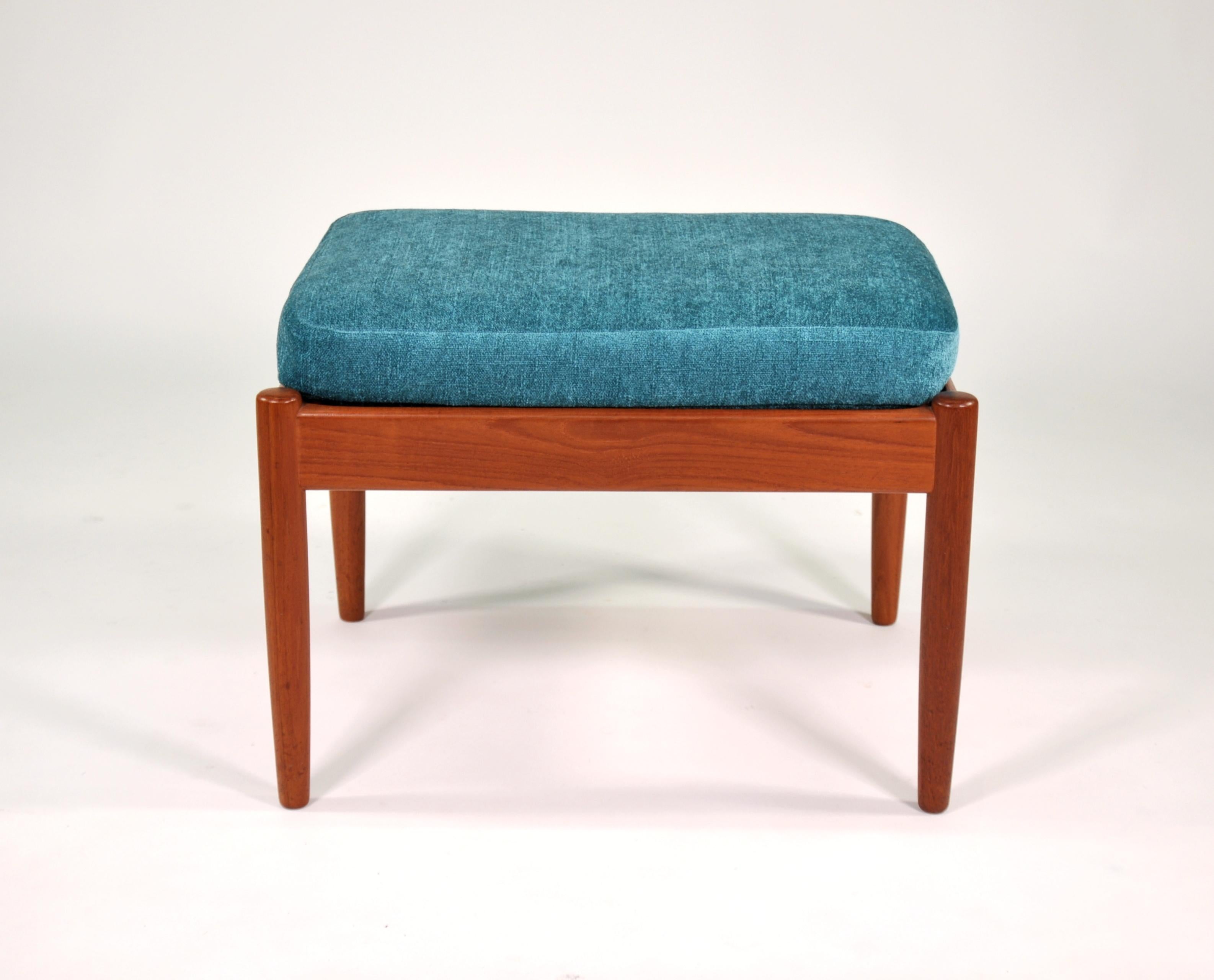 A vintage midcentury teak foot stool by Poul Dinesen, dating from the 1960s. The footrest has a removable cushion with bright teal or turquoise upholstery and simple, clean lines. Made in Denmark. Bears original label.