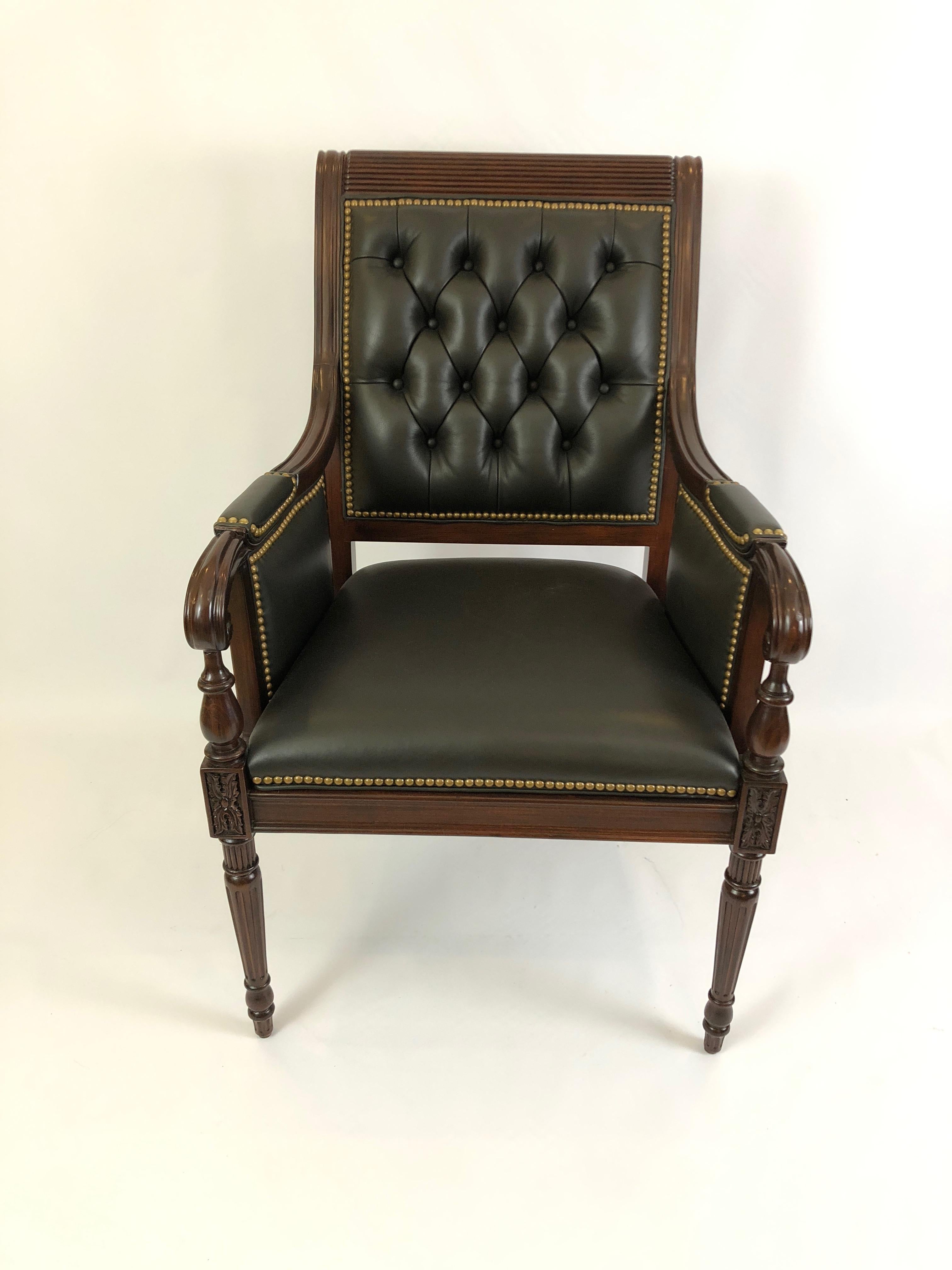 Impressively rich looking substantial arm chair with carved mahogany frame, scrolly arms and tapered legs, upholstered in supple handsome very dark taupe leather. The back is tufted and slants slightly back, and it's all finished with brass