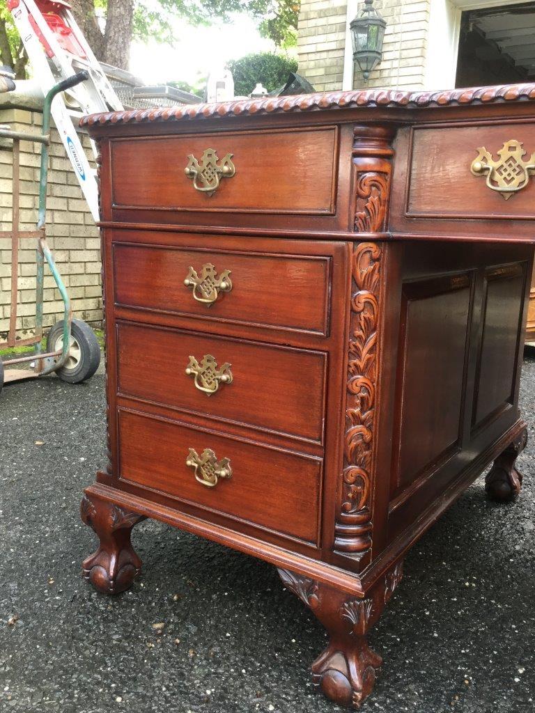 Fabulous large mahogany partner's desk having leather top, multiple drawers and a cabinet on each side. Both sides are identical. There are elegant carvings on the front corners and raised panels both inside and on the exterior sides. This desk