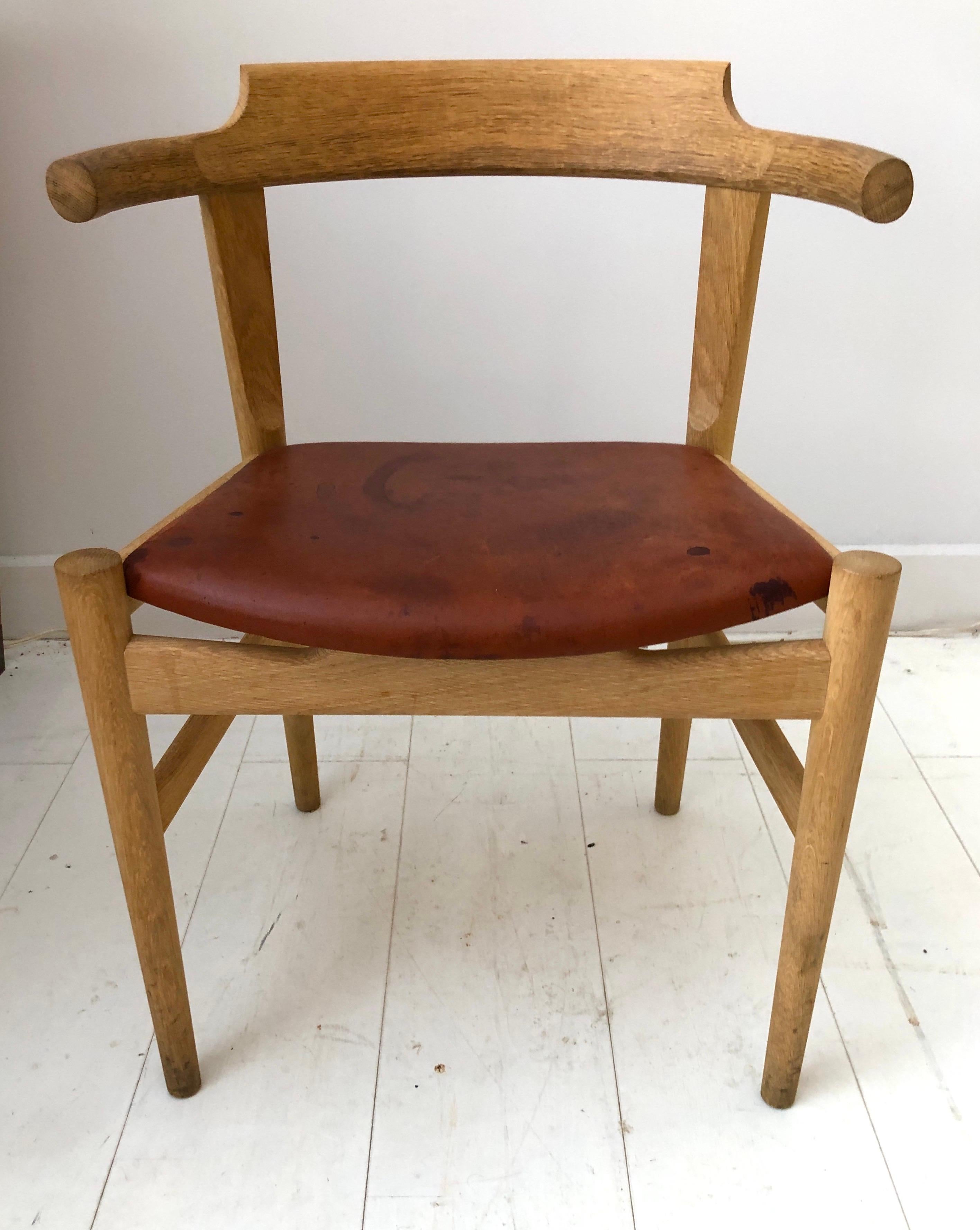  PP68 elbow chair, designed by Hans J. Wegner for PP Møbler, Denmark 1987. Sculpturally carved oak with original cognac  saddle leather seat. Maker’s stamp on underside . In very good vintage condition. The PP68 chair was Wegner's’ final dining