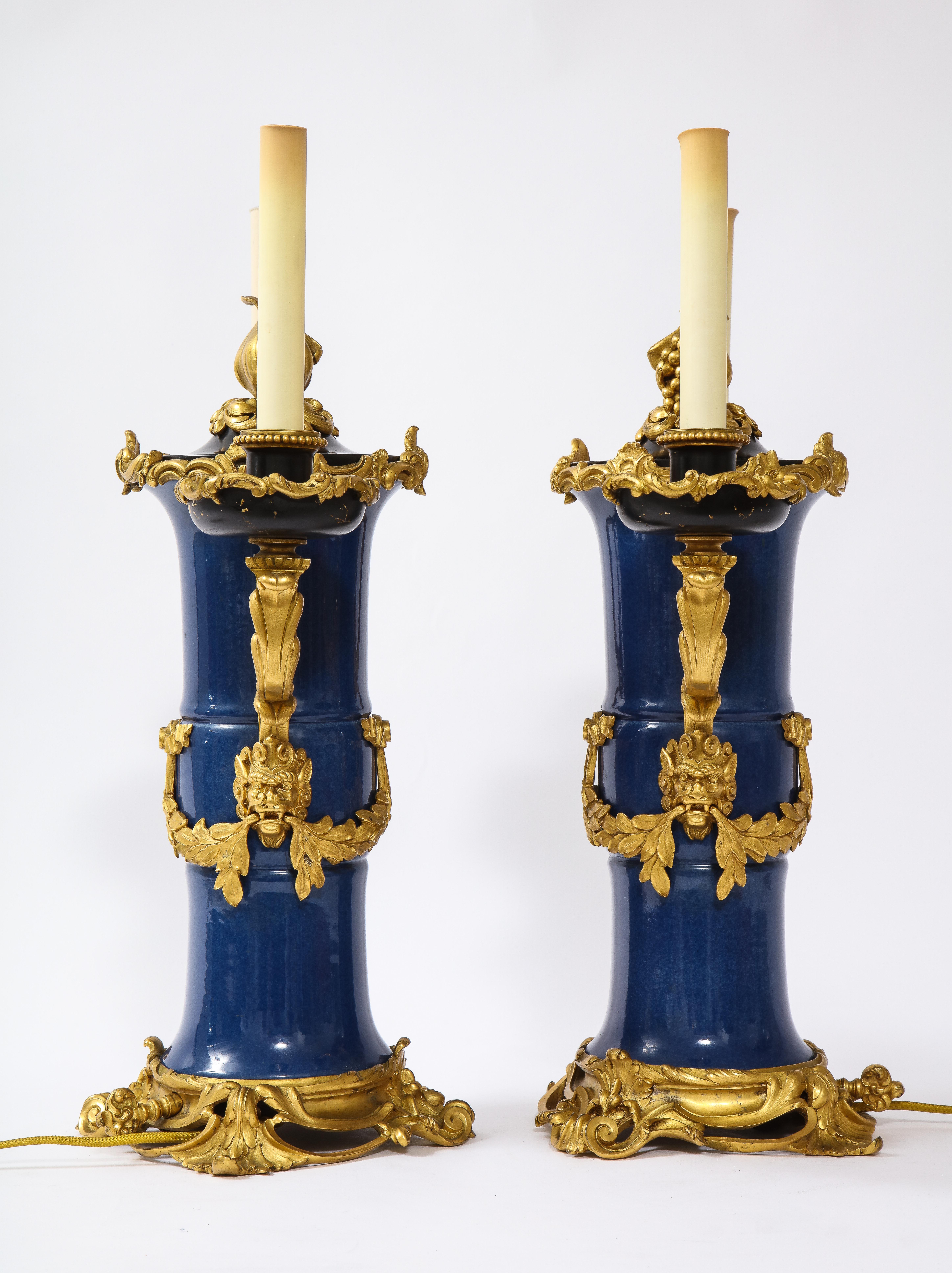 Magnifica coppia di candelabri in porcellana Ormolu e blu cinese del XIX secolo, attribuiti a Caldwell. Ogni candelabro è costituito da un vaso cilindrico in porcellana con un collo leggermente svasato e una base arrotondata. La superficie della