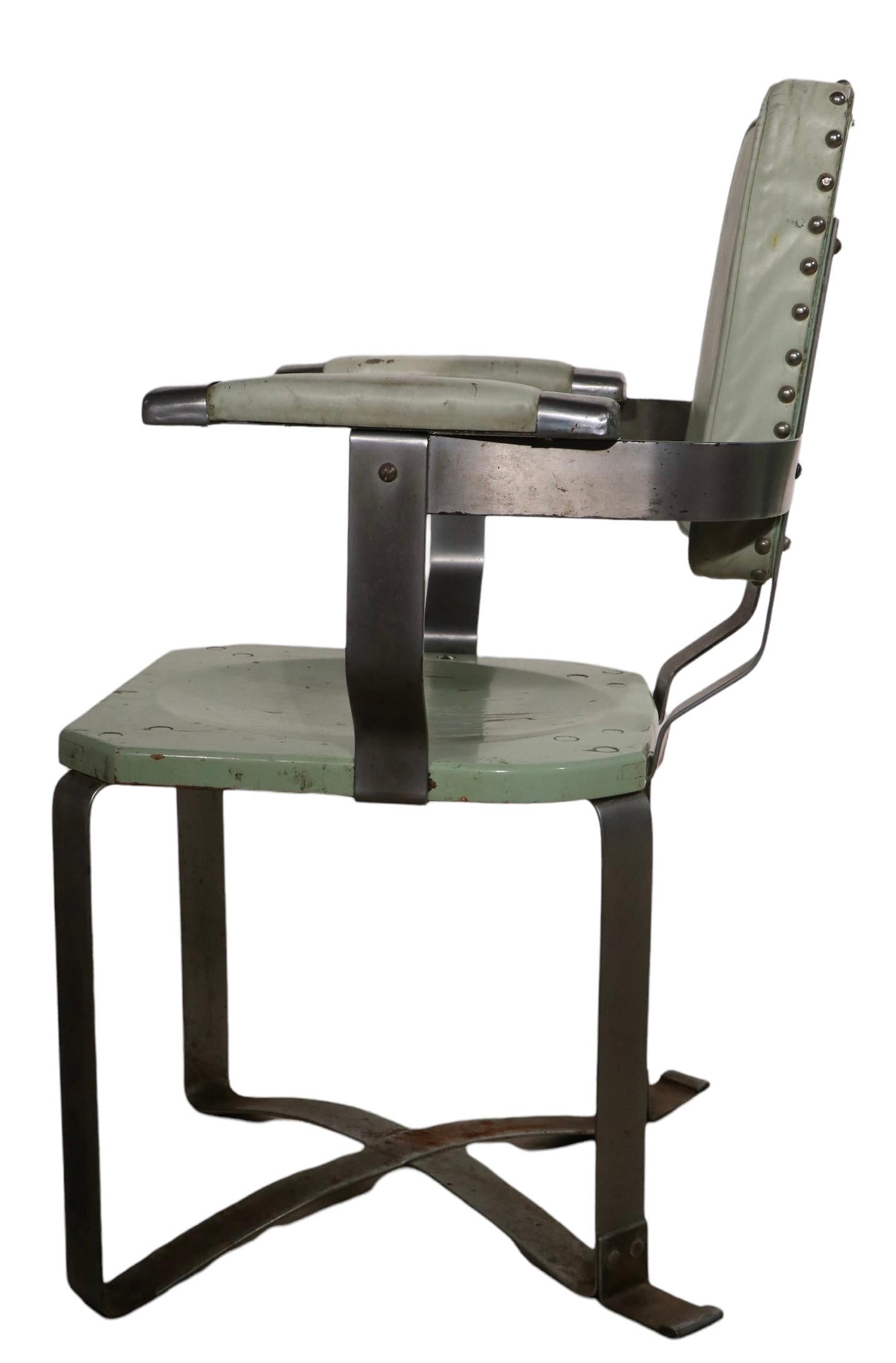 Unusual pair of period Machine Age arm chairs, having chrome plated steel frames, wood seating backrests, and leather upholstered armrests. We believe these could be early prototypes, as we have not seen this form before, nor can we find any
