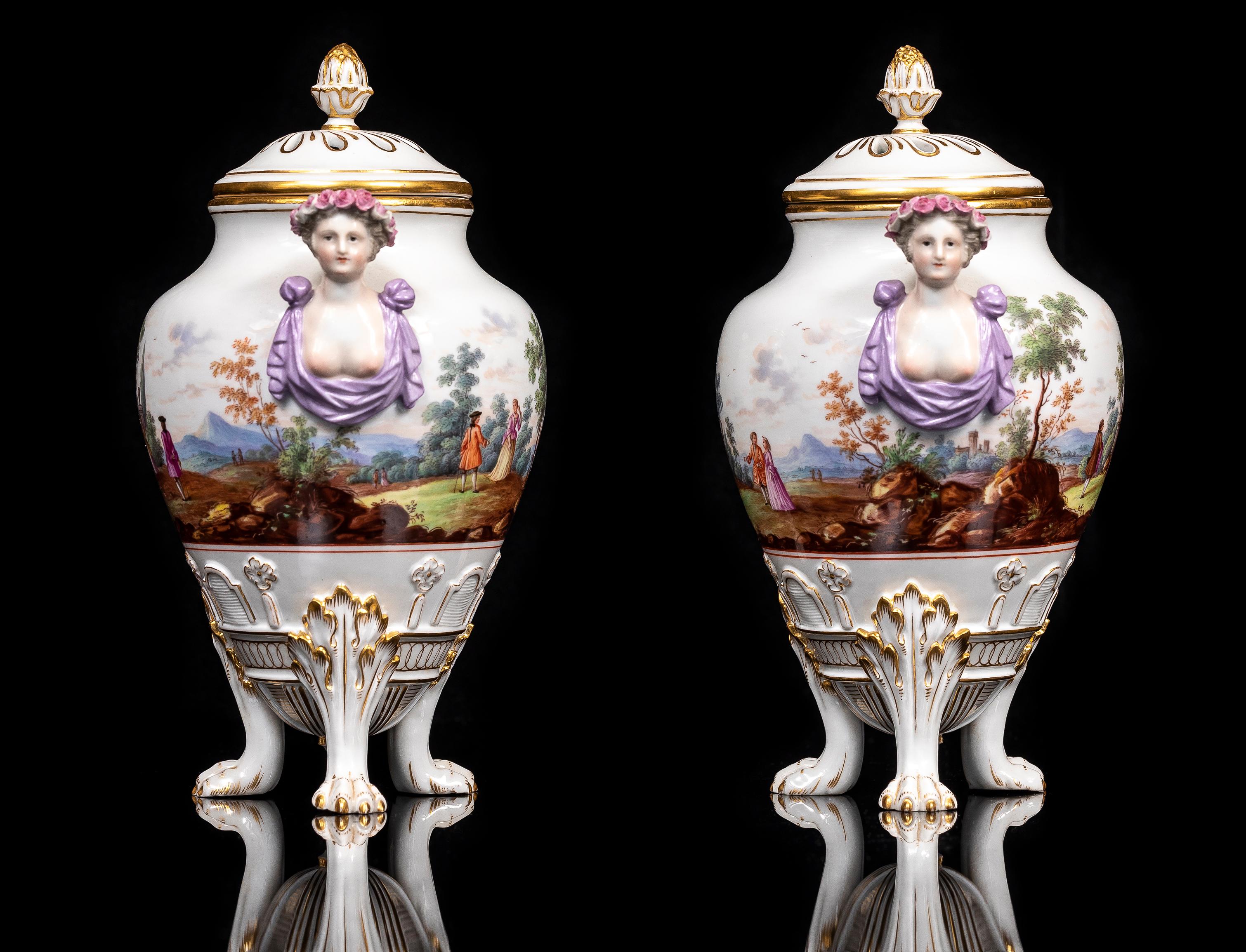Coppia di potpourri coperti in Meissen Porcelain del XIX secolo, con scene di paesaggi pittorici, zampe di leone e manici di fanciulle figurate.  Ogni vaso a forma di urna poggia su tre piedi a zampa di leone graziosamente incurvati e ornati da