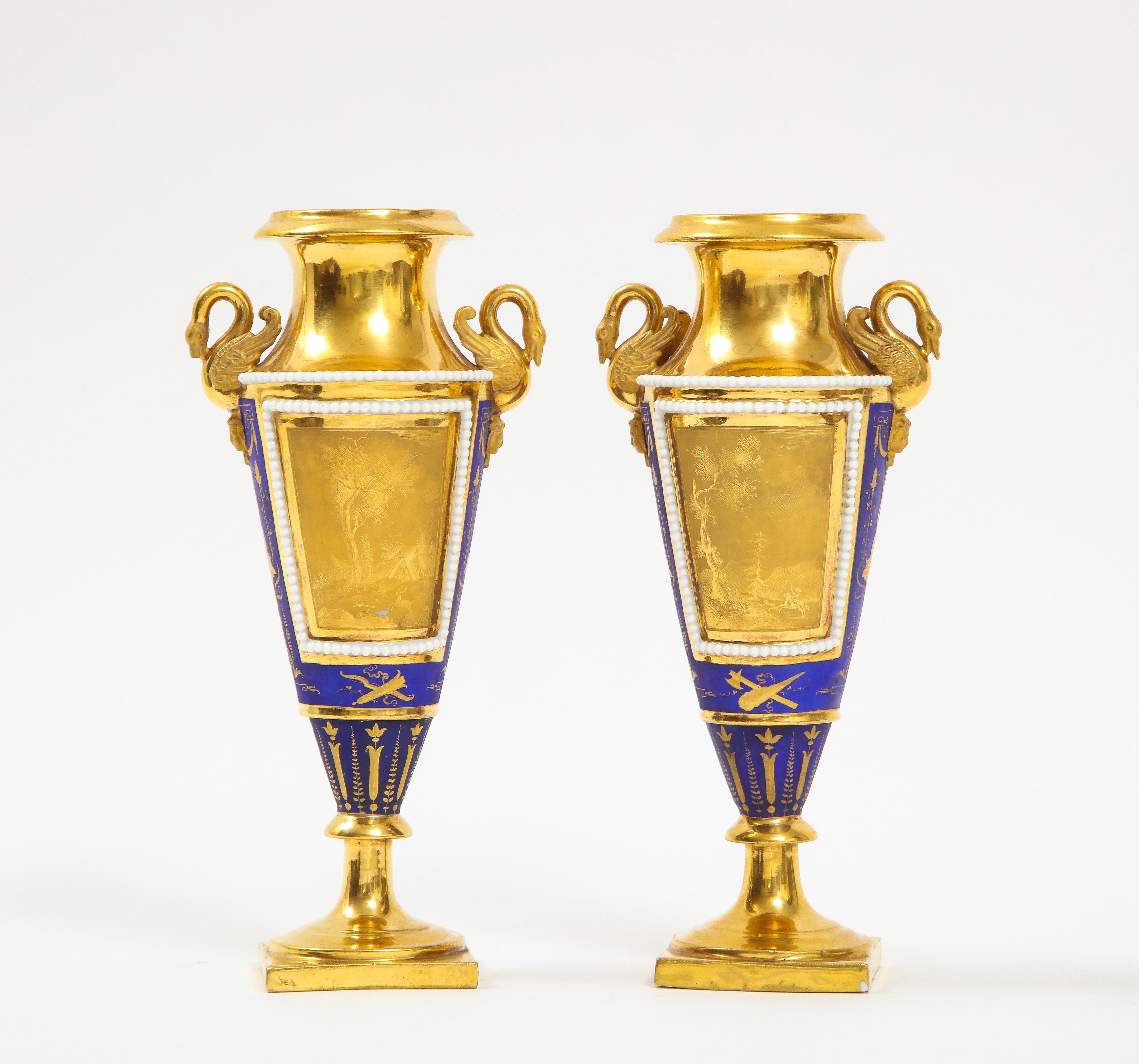 A fantastic quality pair of Russian Empire cobalt blue and gold ground swan handle porcelain vases. Each piece is of Amphora form with a gorgeous 24K gold matted, burnished, and shiny front and backside decoration. The front panels consist of a