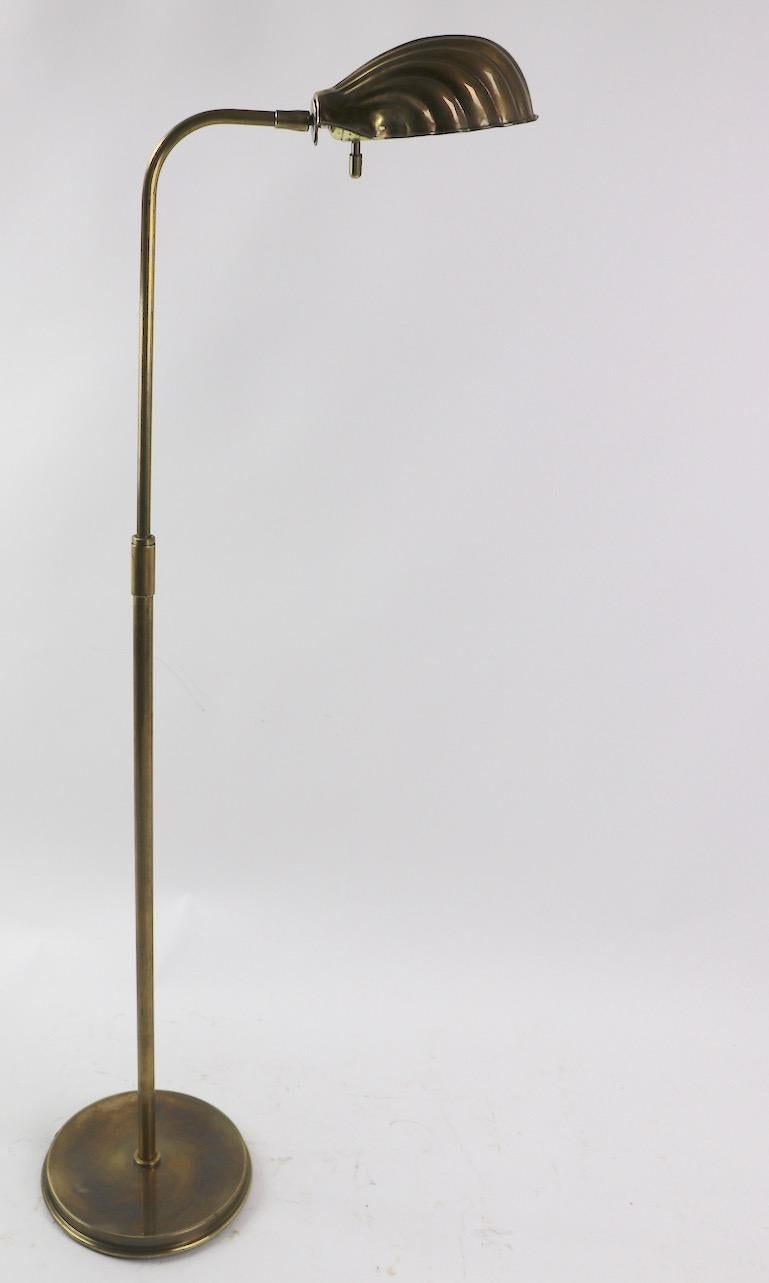 Pair of adjustable brass floor lamps have shell form shades. The lamps will adjust in height (Highest 50 x Lowest 45 inch) and the shell shade (7.5 W x 5 D inches) tips to direct the light. Diameter of base 9.5 inches. Both lamps are in very good