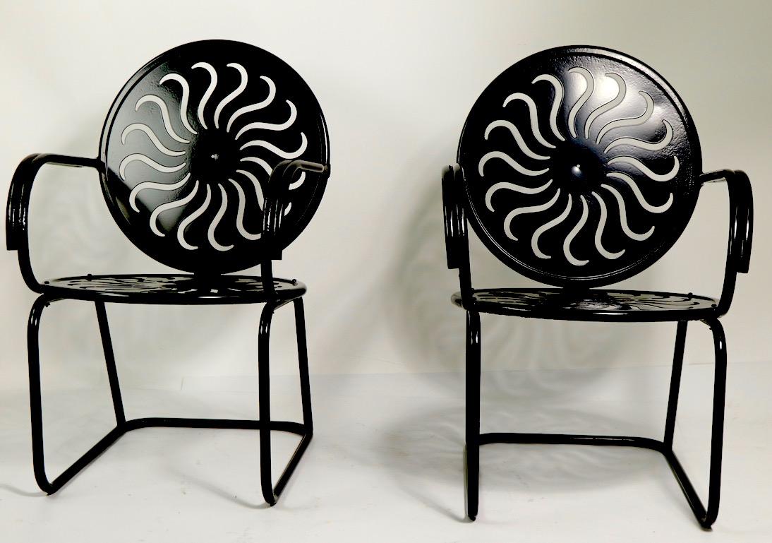 Wonderful pair of patio, garden, porch chairs in cut out swirl pattern steel with tubular steel frames. These a=chairs are circa 1930s and have been newly restored with semi gloss black powder coat finish, resulting in a slick, graphic and bold