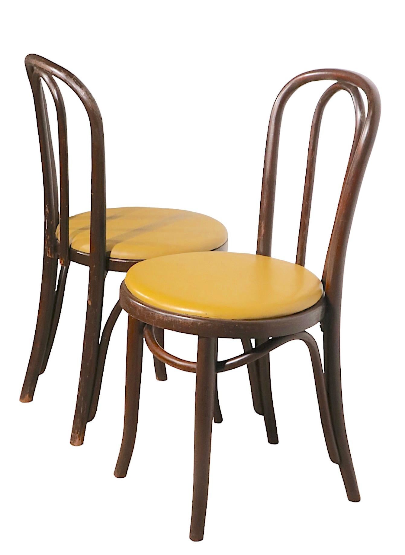 Chic, sophisticated pair of cafe, bistro style dining chairs of bentwood frames with vinyl pad seats. These chairs are in very good vintage condition, showing some cosmetic wear, normal and consistent with age. Offered and priced as a pair,