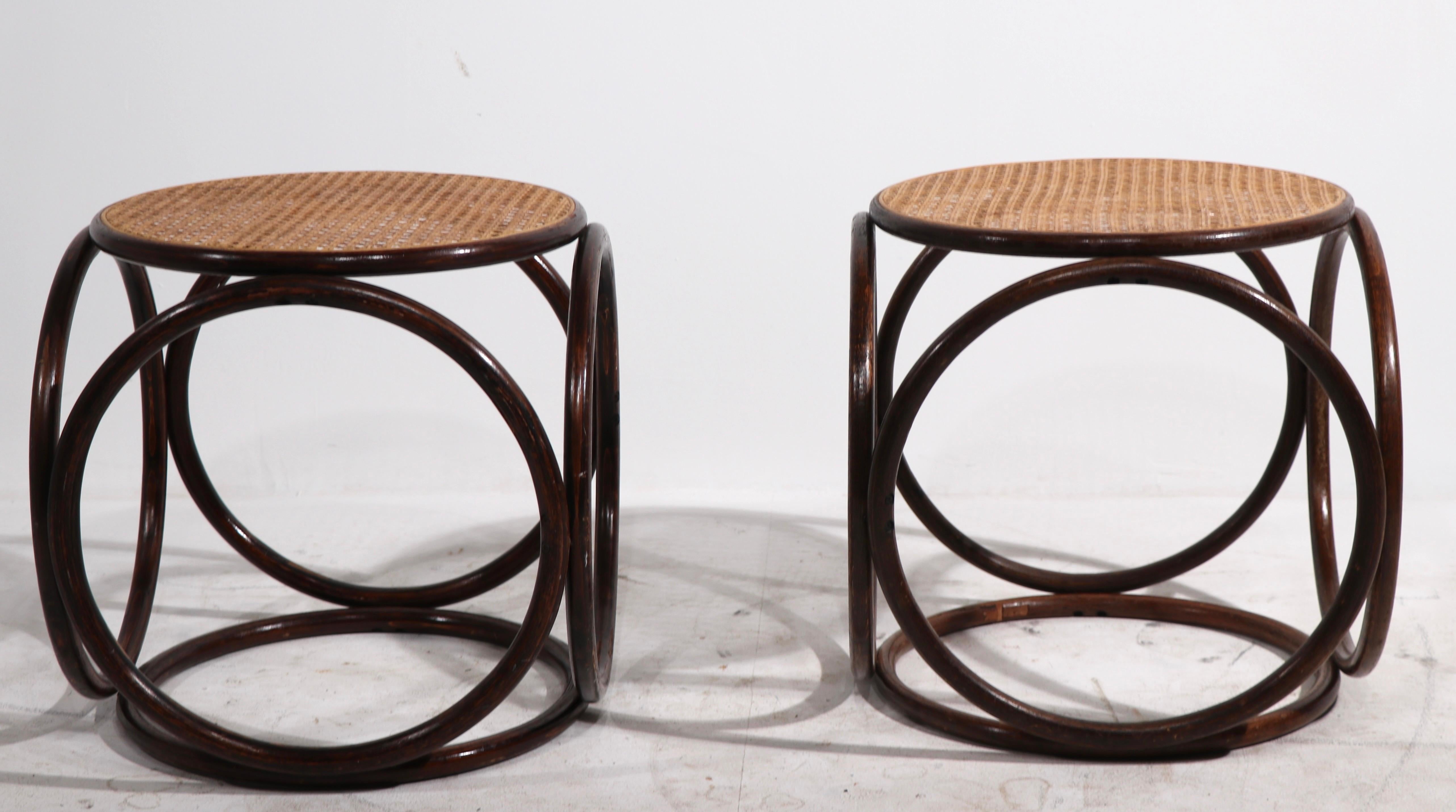 Pair of iconic Thonet bentwood and caned stools, by Thonet. Unusual to find these as in pairs, both are in good original condition showing only light cosmetic wear normal and consistent with age. Priced and offered as a pair.
 