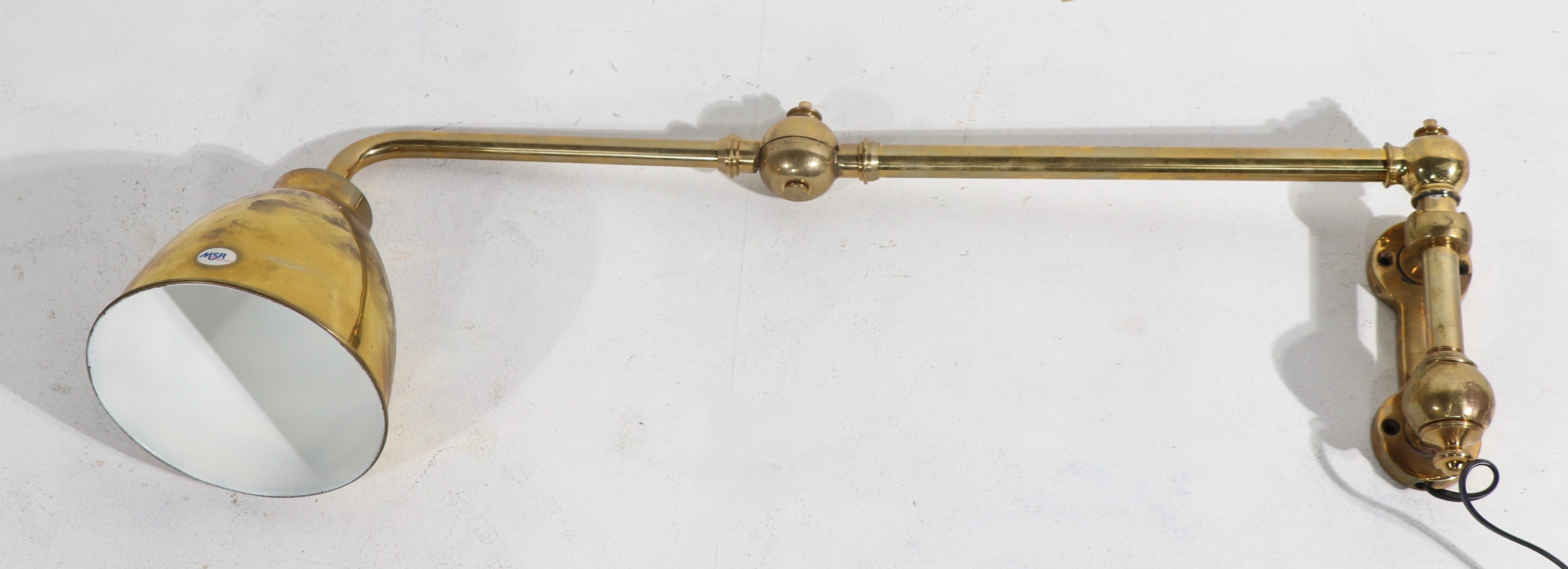 Nice pair of flex, or swing, arm sconces in solid brass. Each sconce features the original wall mount backplate, two tubular arms connected with a knuckle joint, and a bell shaped hood shade. Both are in working condition, and accept standard size