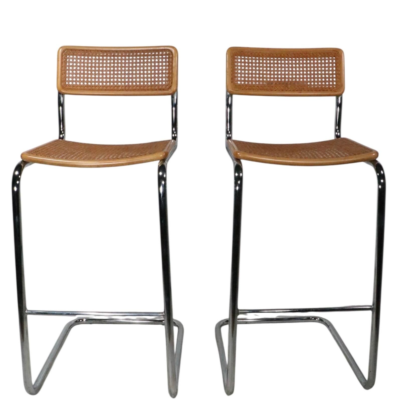 Voguish pair of bar height Cesca stools, made in Italy c. 1970's. The stools feature caned seats and back rests with wood frames, mounted on bright tubular chrome cantilevered legs. Both stools are in very fine, original, clean and ready to use