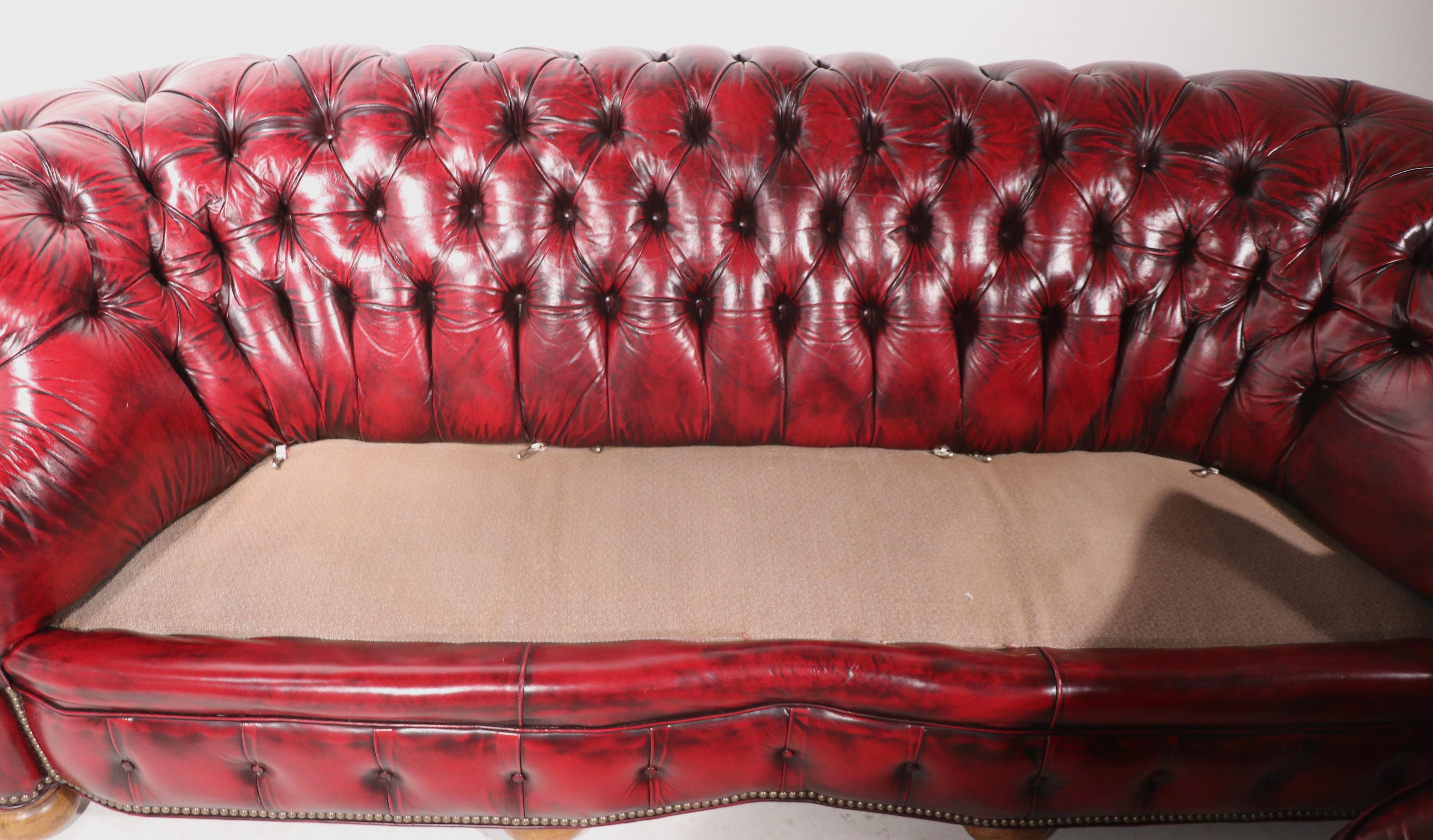 Phenomenal pair of Chesterfield sofas, having fully tufted upholstery, brass stud trim, tied spring construction and down filled seat cushions. Top quality materials, construction, both are in very fine, original clean and ready to use