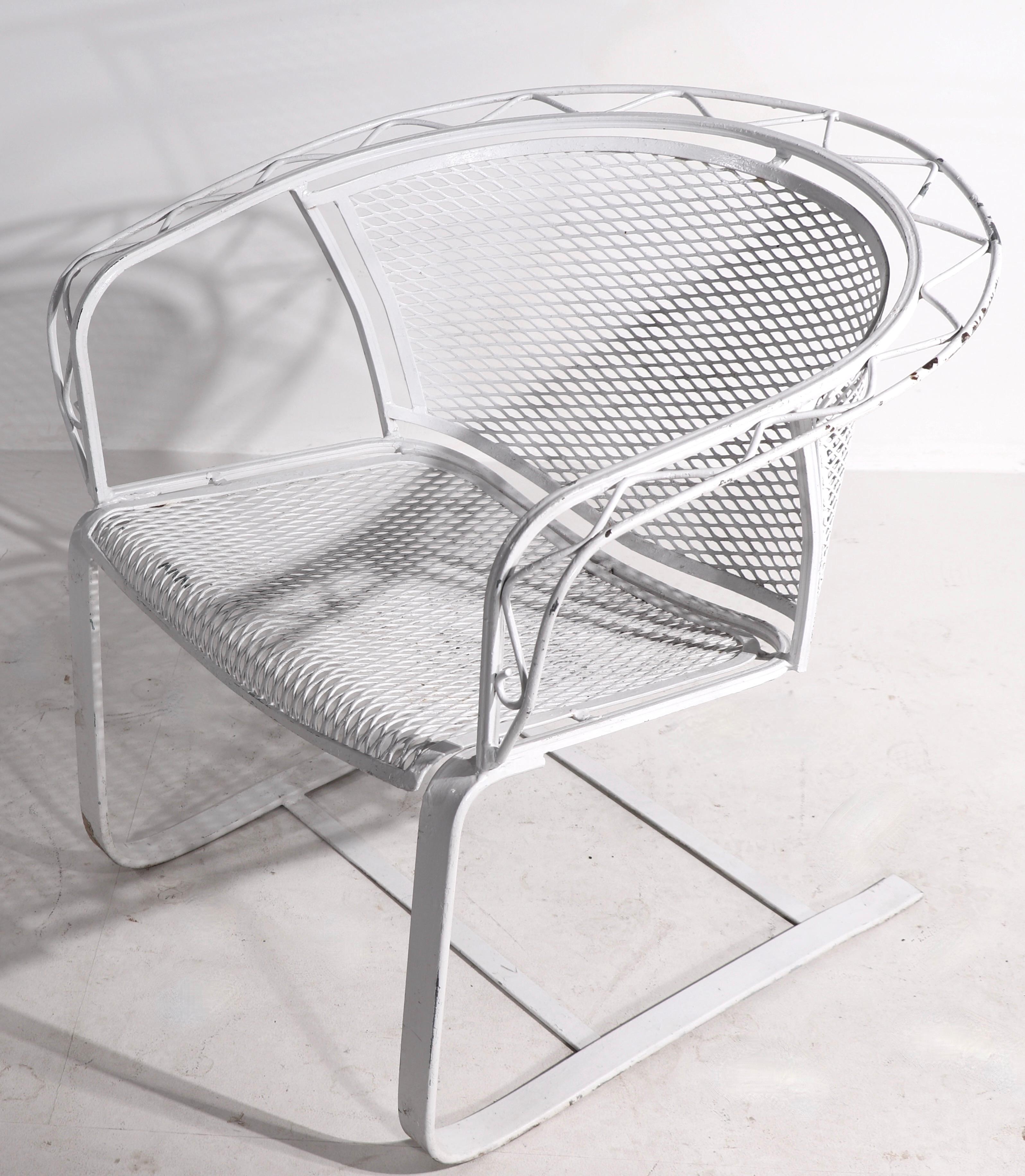Great pair of cantilevered lounge chairs by Salterini. The chairs feature a wrought iron zig zag trim which runs along the back and down the arms, metal mesh seat and back, on heave wrought iron cantilevered bases. Both are in very good condition,