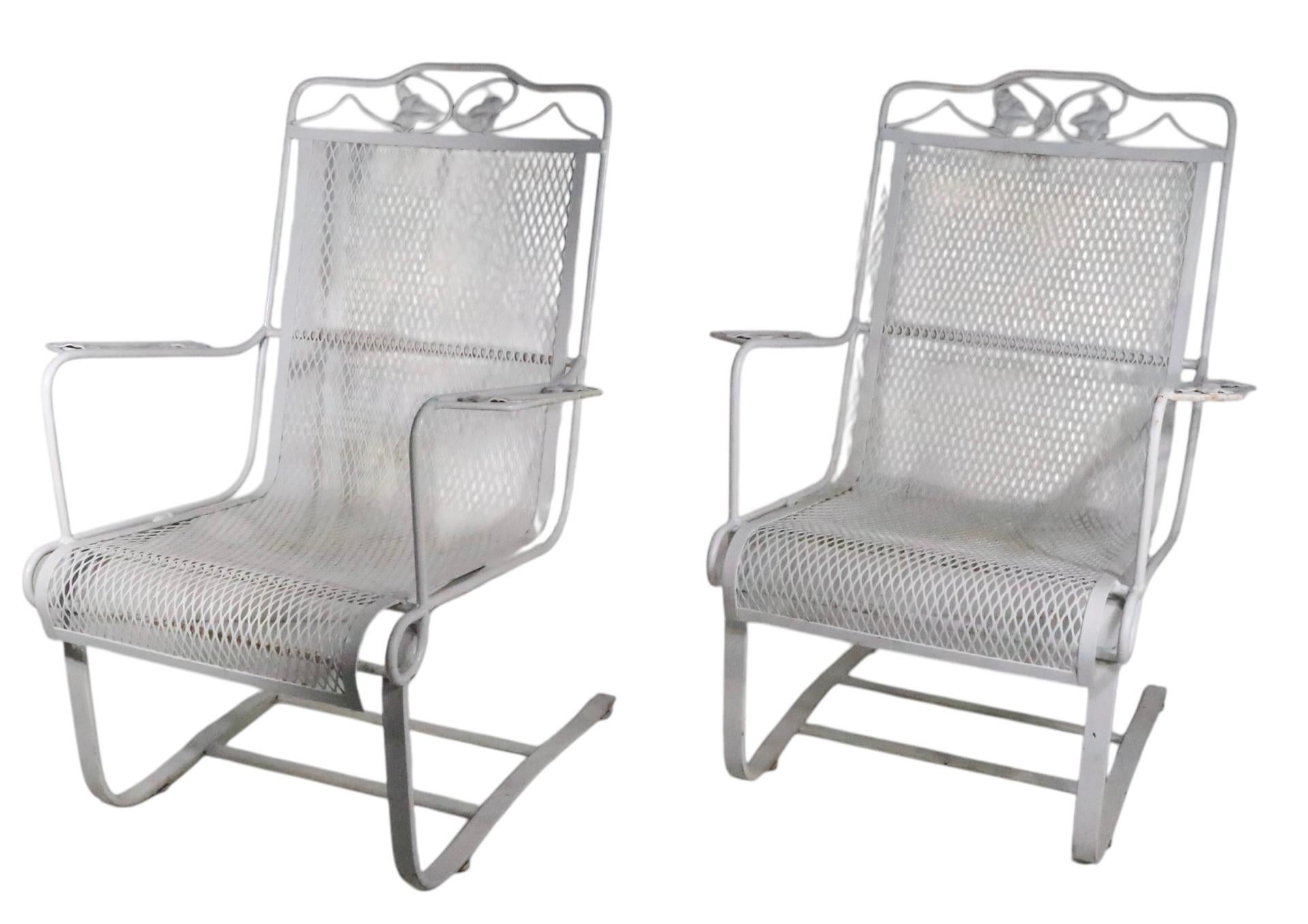 Pr. vintage garden, patio, poolside cantilevered lounge chairs attributed to the Woodard Furniture Company, circa 1960/70's. The chairs feature wrought iron frames, with a continuous metal mesh seat and backrest. The cantilevered base creates an bit
