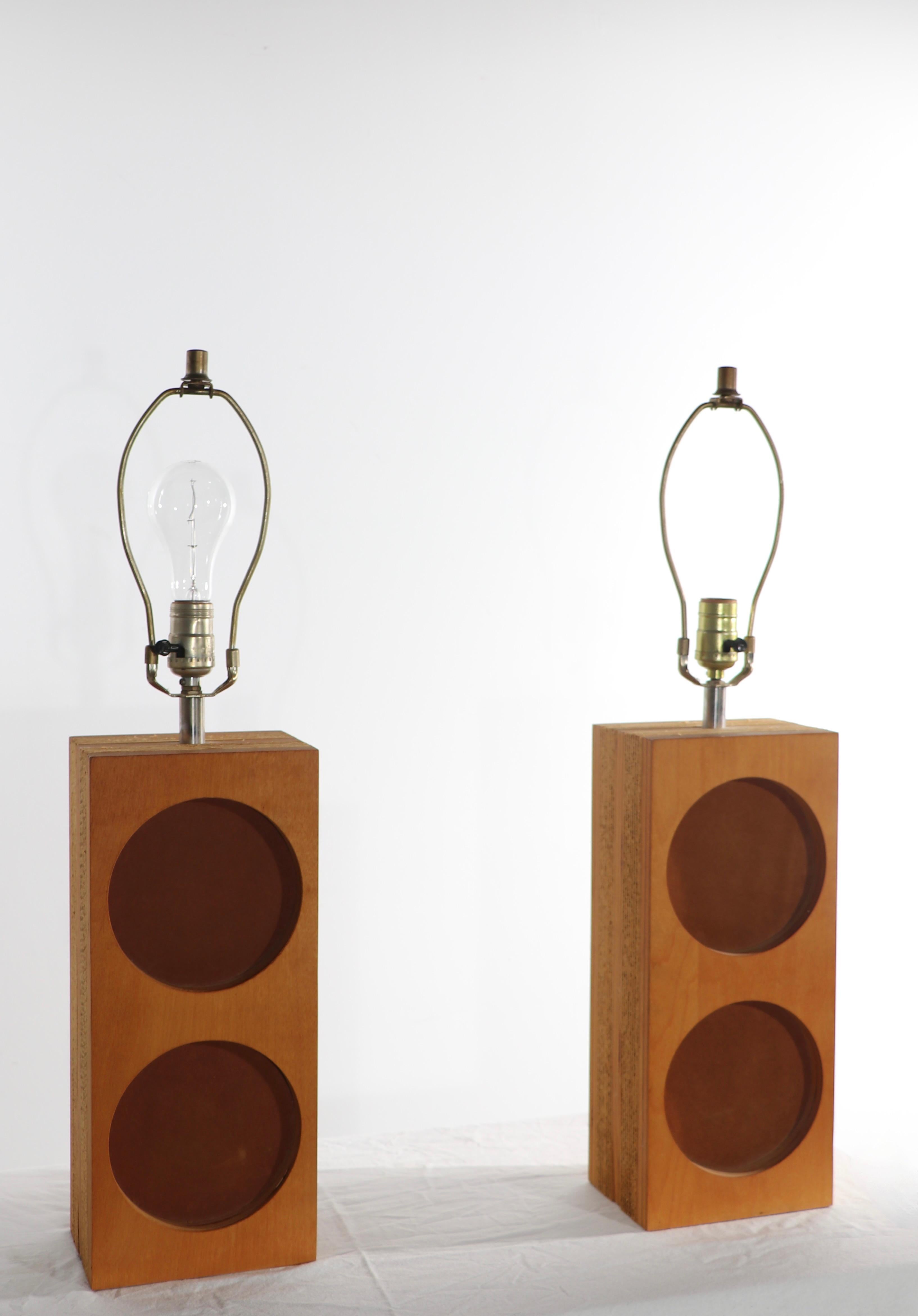 Extraordinary pair of architectural lamps, attributed tonGregory Van Pelt, in the style of Frank Gehry . The lamps features a layered cardboard and plywood rectangular body with circular cut out disks lined with tan ultra suede. Both are in very