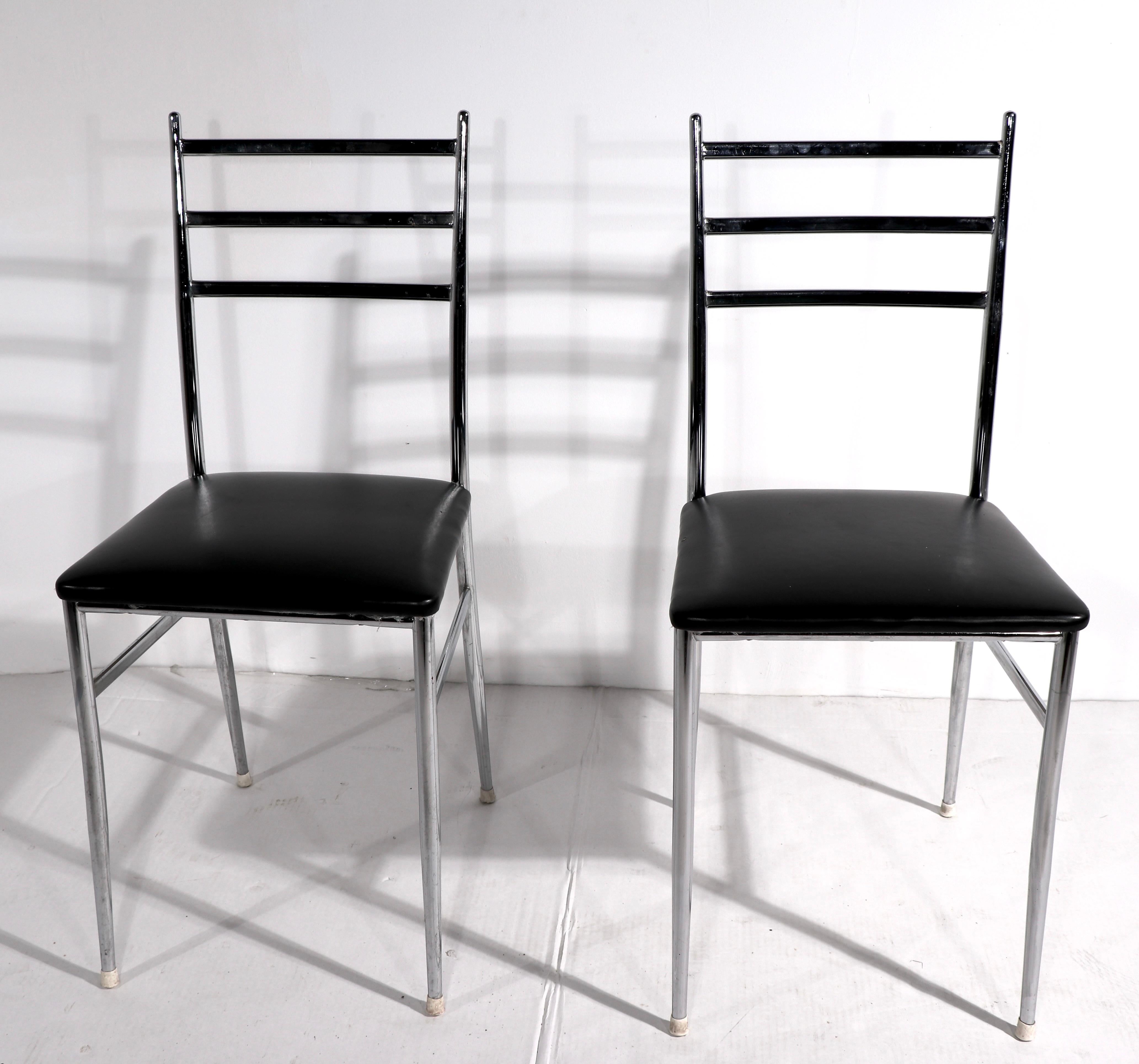Stylish pair of chrome ladder back chairs, design reminiscent of the iconic Ponti Superleggera chair. The chairs are in very good original condition, the black seats have inconsequential flaws to the upholstery, normal and consistent with age.