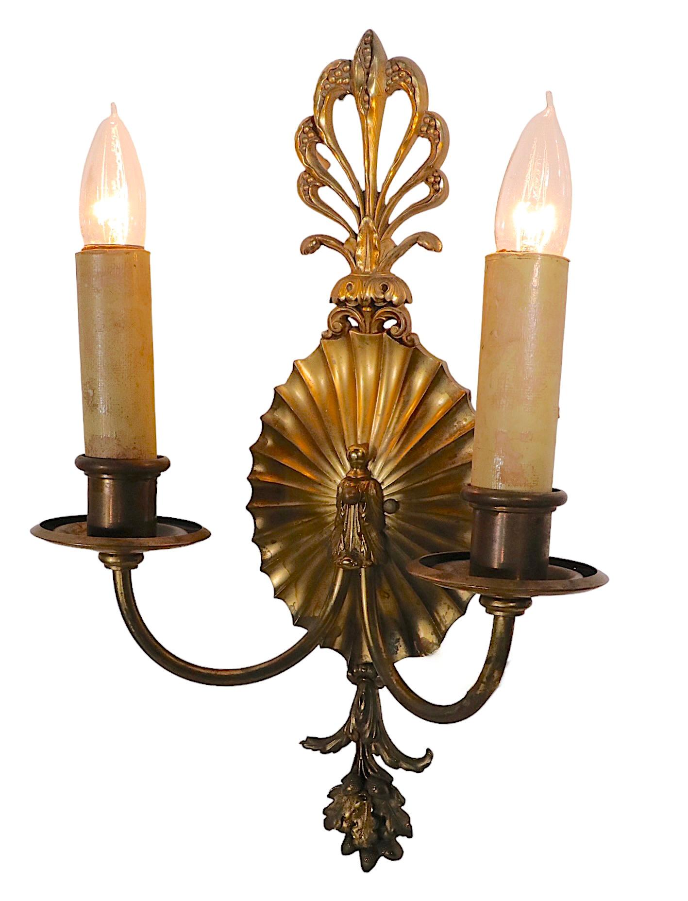 Impressive pair of formal, classic style wall sconces by Edward F. Caldwell. Each sconce has two candle style arms, and a cast brass backplate with decorative foliate castings. Both are in very good original, working, condition showing only light