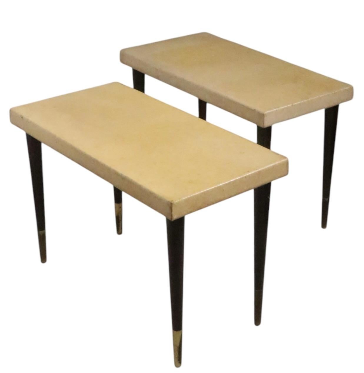 Chic pair of cork top side, or end tables, designed by Paul Frankl, made by Johnson Furniture, retailed by John Stuart circa 1940's. The tables feature thick rectangular cork tops, with elegant tapered wood pole legs, with original brass sabot feet.