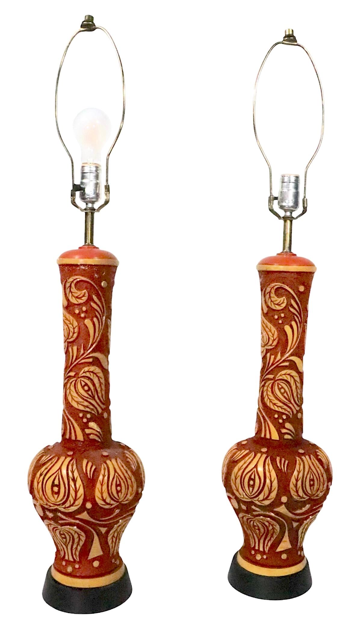 Voguish pair of mid century ceramic table lamps, having textured  fond rouge avec un décor de feuillage stylisé en relief dans les tons jaunes. Le tout monté sur des bases noires. Les lampes sont en très bon état, propres, d'origine et