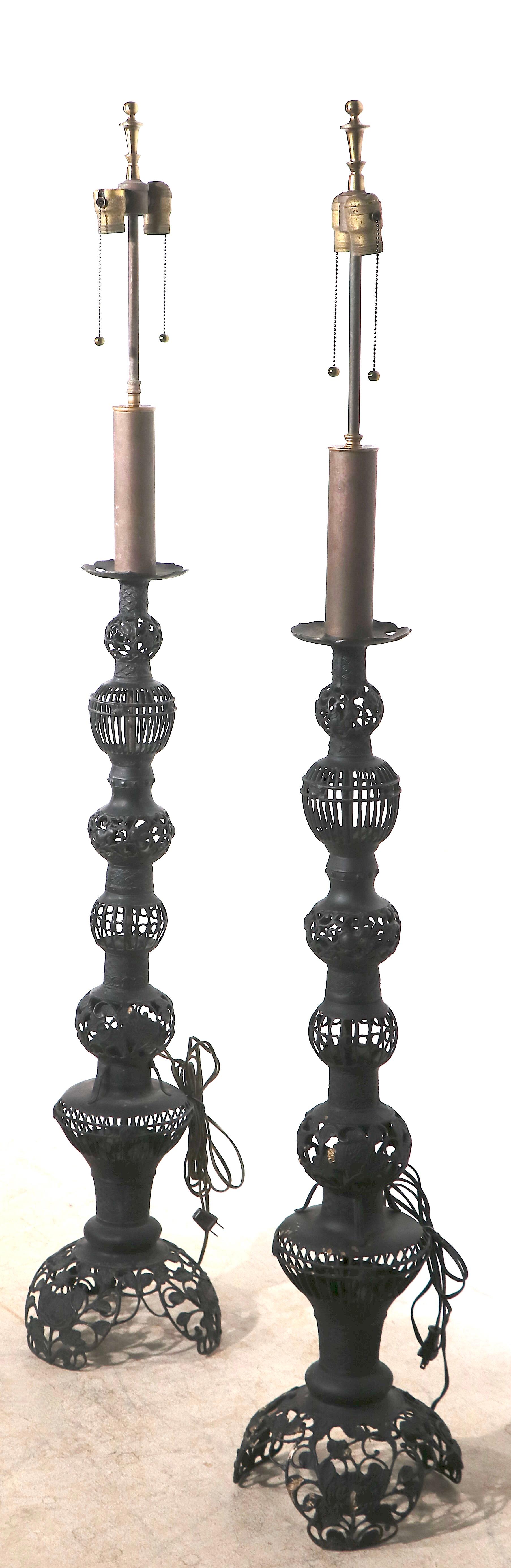Pair of decorative floor lamps, having pierced metal foliate bodies, in alter black paint finish. Both are non working condition, and have been newly professionally rewired. Specific condition report as follows:
 One brass socket cap is missing,