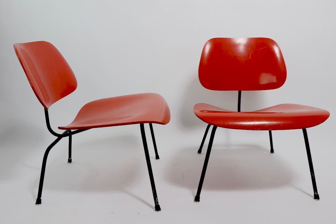 Ein ikonisches Paar LCMs von Eames für Herman Miller in späterer orange-schwarzer Lackierung. Diese Stühle sind strukturell solide und stabil, beide haben eine spätere, aber nicht neue, orangefarbene Lackierung auf den Holzsitzen und -rücken, und