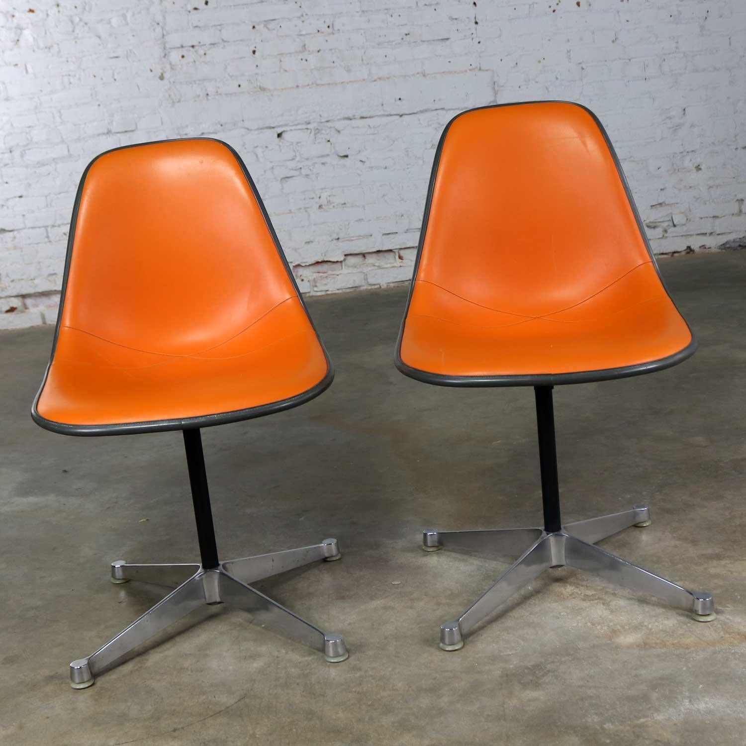 Fabulous pair of Herman Miller Eames pivoting side shell chairs on contract base or PSC chair. Their greige fiberglass shells are upholstered in orange vinyl. They are in wonderful vintage condition with only the normal wear for their age. There is