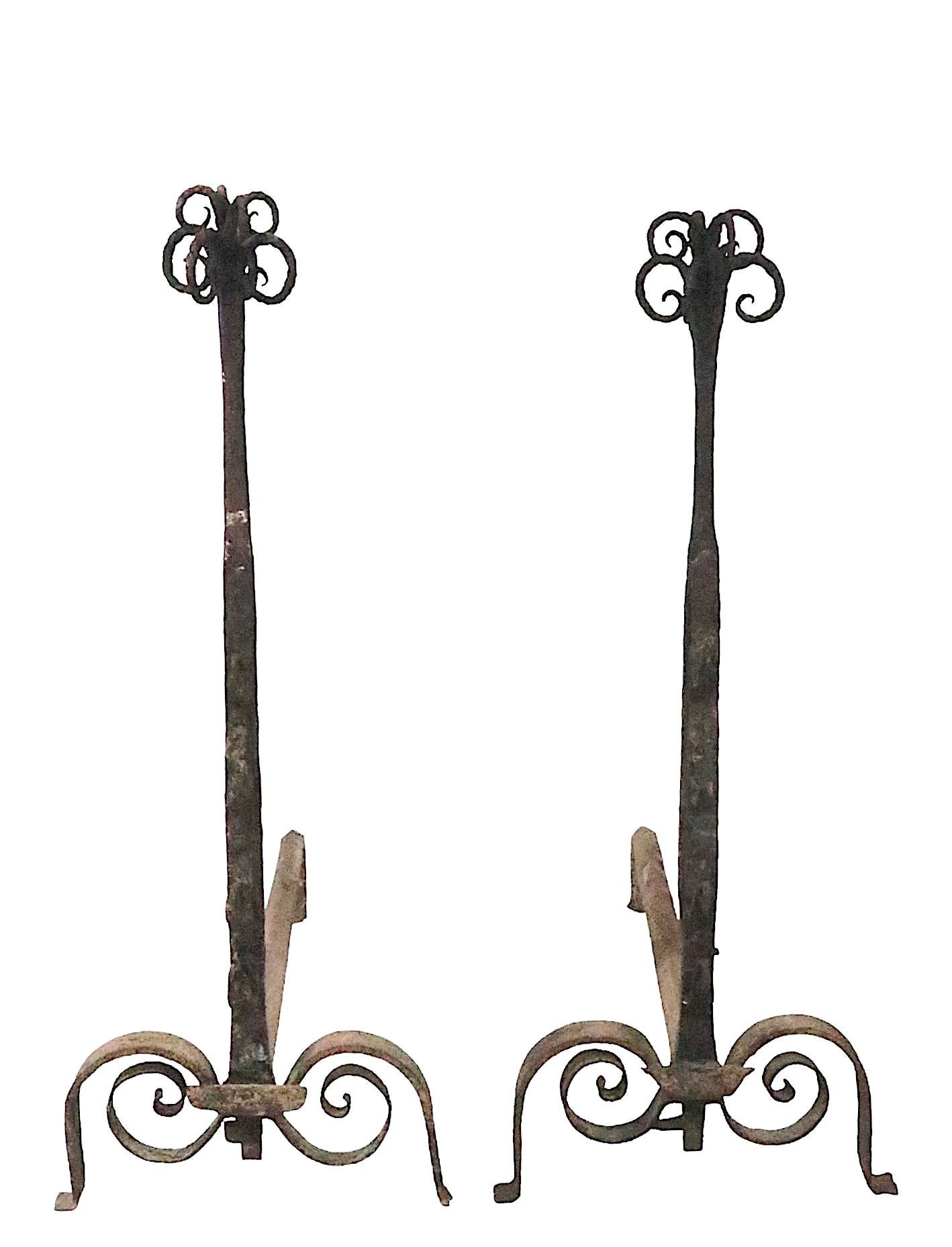 Great pair of hand forged iron andirons, probably Continental.possibly French in origin, early 19th C or 18th C vintage. The andirons feature an organic plant like top with twisted metal curlicue form elements, the vertical shafts have wrought hooks
