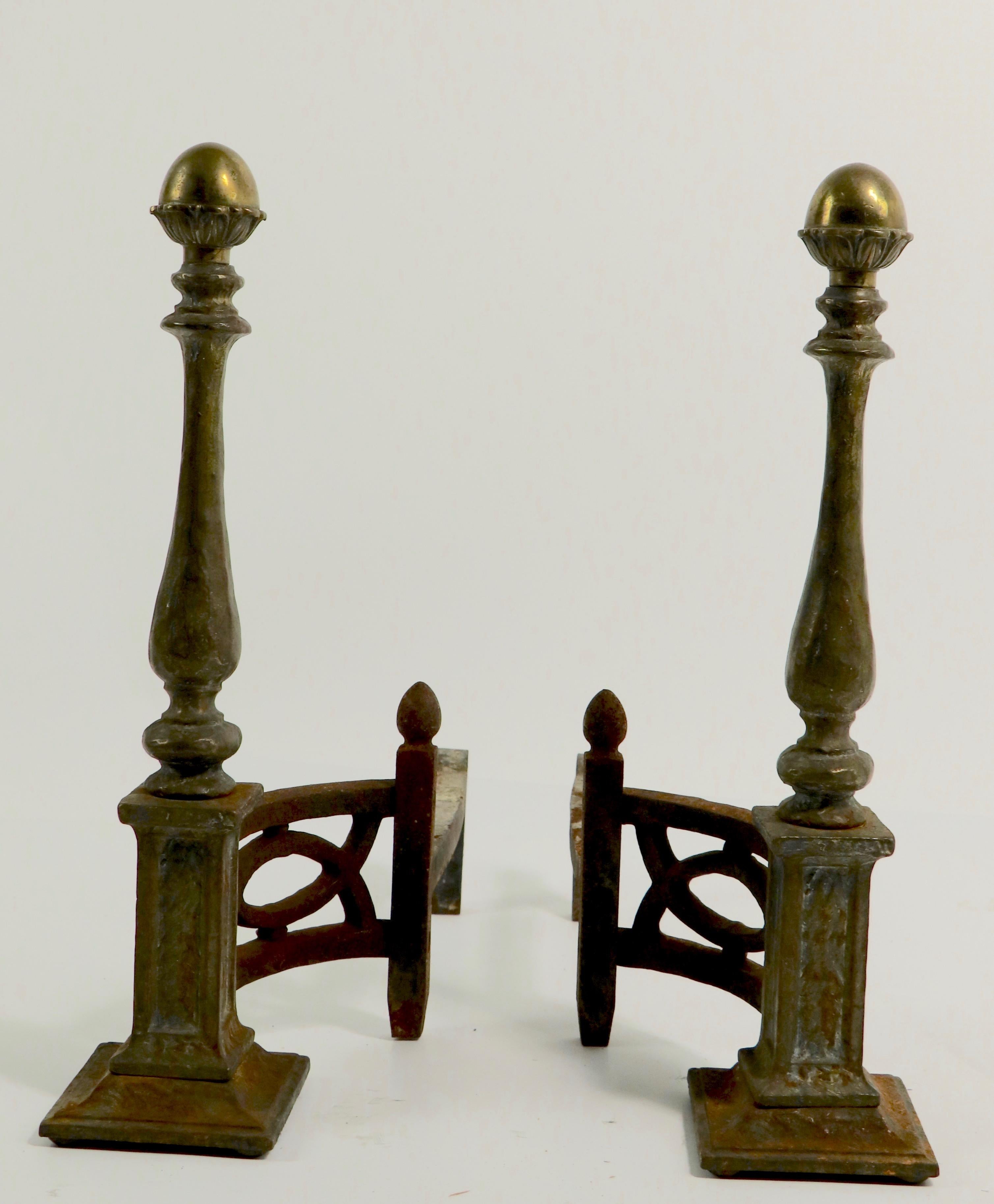 Very nice pair of English Arts & Crafts, Mission style andirons having solid cast iron bases and vertical standards with a decorative cast brass finial top.