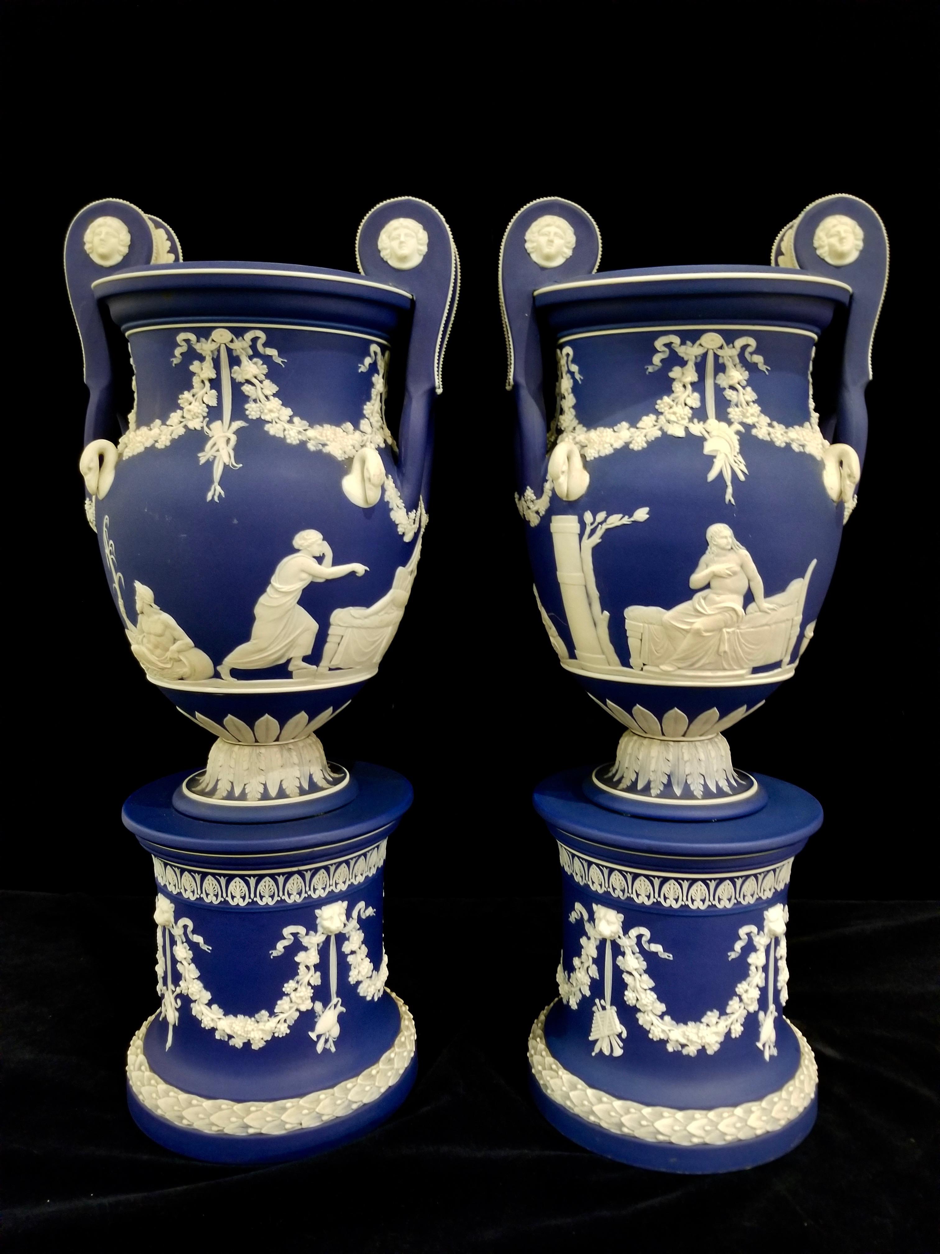 An exquisite and quite rare pair of 19th century English, Staffordshire, Jasperware blue ground Wedgwood vases with neoclassical subjects on rounded plinths, stylistically attributed to John Flaxman. Each of these vases are in exceptional condition