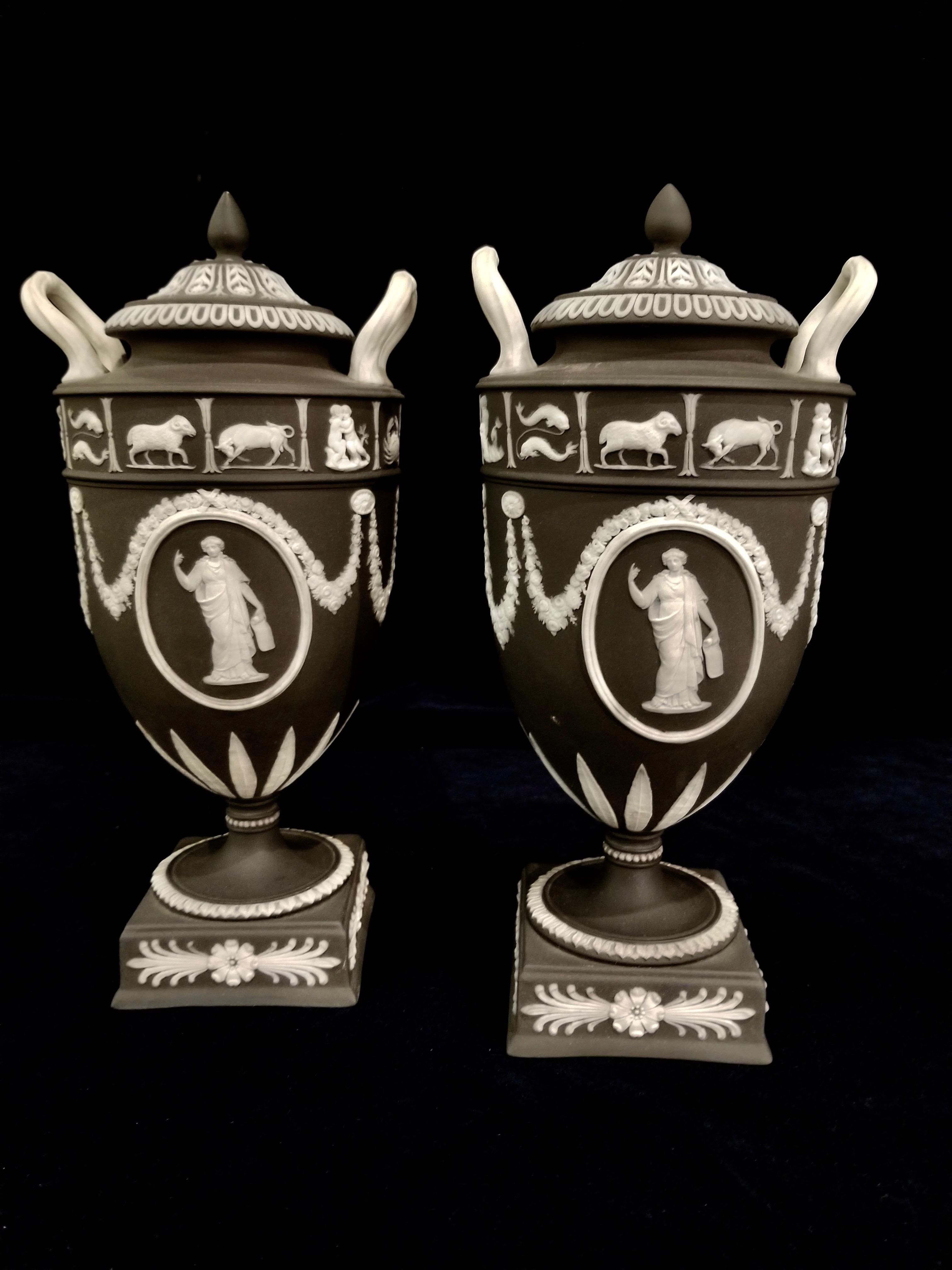 An exquisite pair of 19th century English, Staffordshire, Jasperware black ground Wedgwood vases with zodiac subjects. Each of the amphora form with original black basalt lids. The body of each is decorated with neoclassical subjects in white