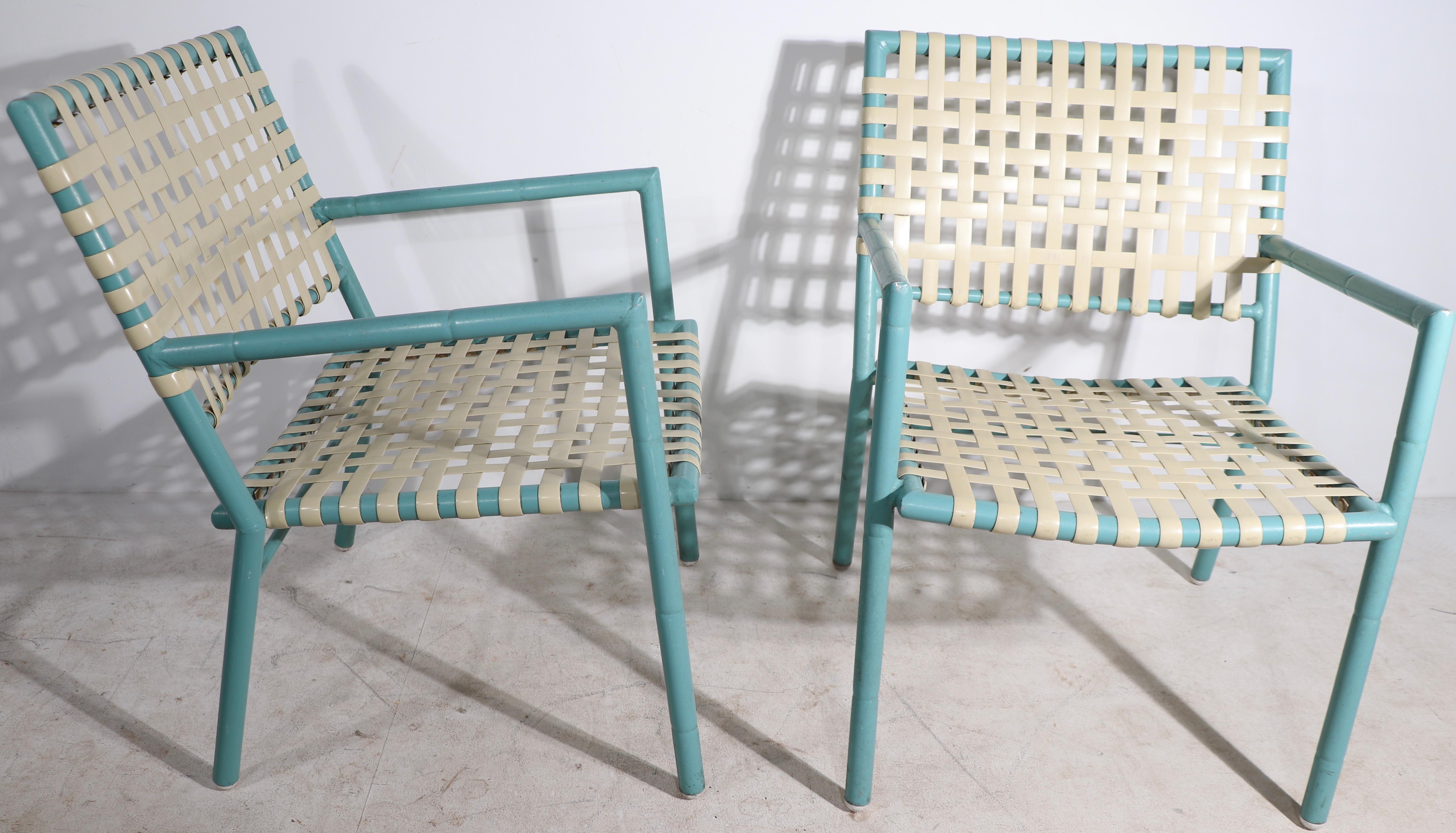 Chic pair of poolside, patio, garden chairs having aluminum frames with a faux bamboo motif, and woven plastic strap seats and backs. Made by noted American leisure furniture company, Hauser, in the style of Brown Jordan. 
 Priced and offered as a