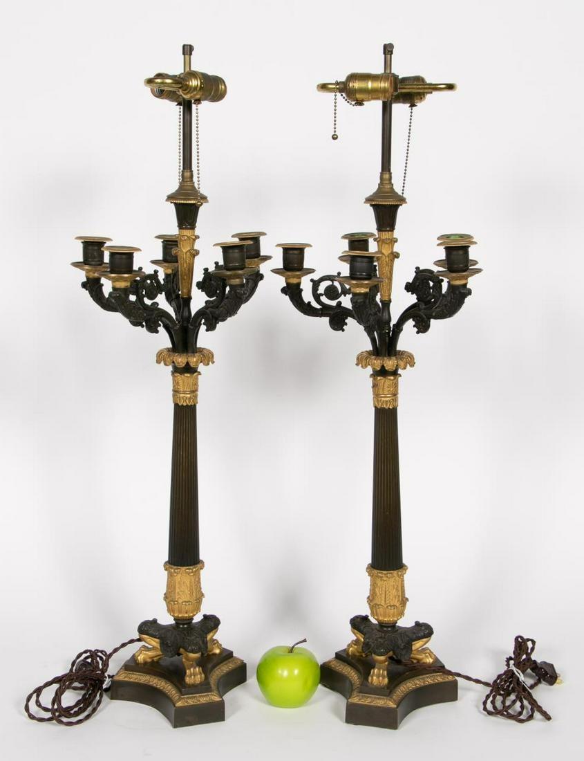 French, 19th century. Cast patinated bronze five light candelabra, now mounted as double socket lamps with gilded column form with foliate and anthemion, capitals, fluted shafts, acanthus detail, rising on triparte paw foot base with conforming