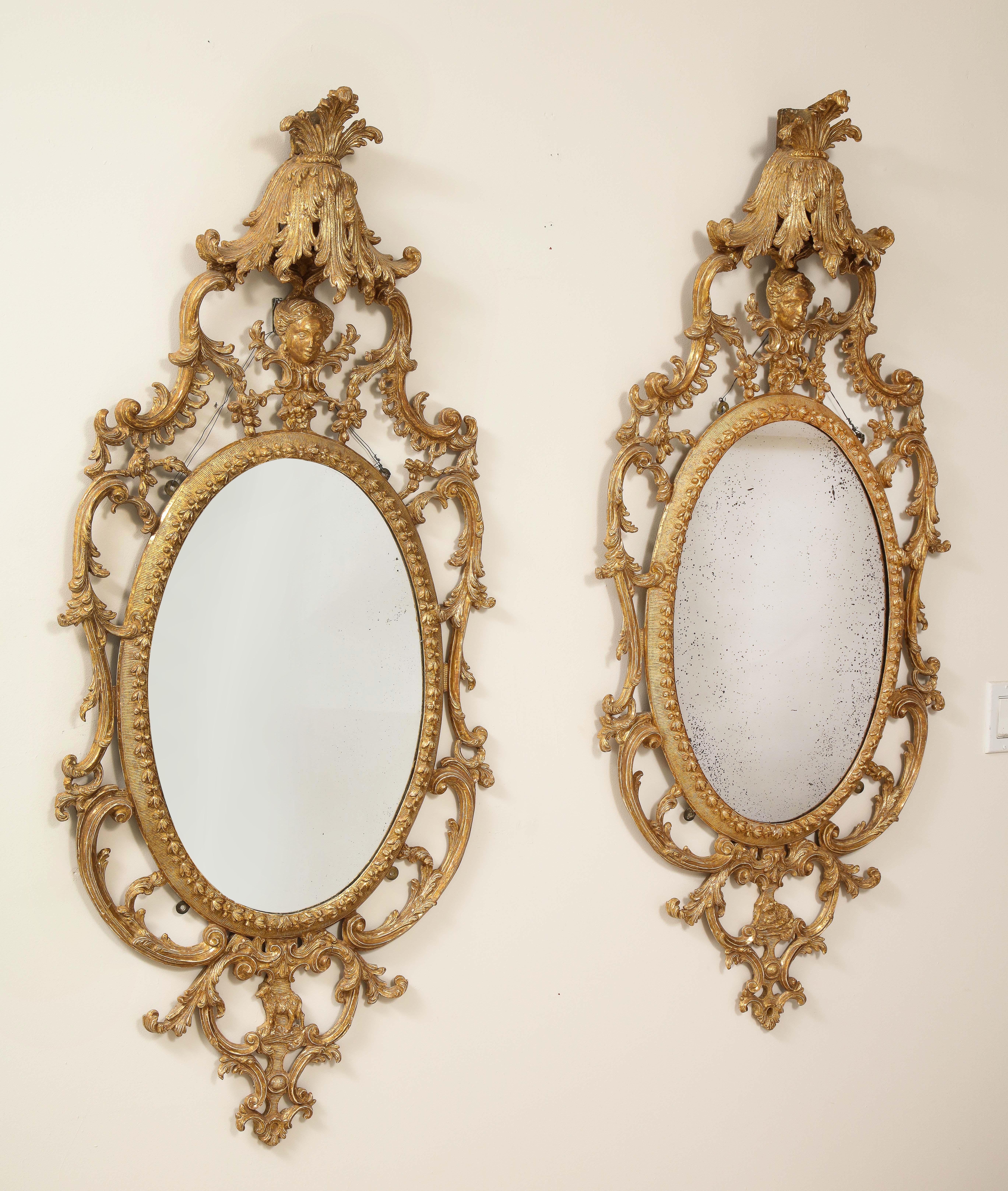 A fantastic and extremely rare pair of George III period gilt Carton-Pierre and giltwood oval mirrors in the manner of John Linnell. Each mirror is gorgeously hand carved with meticulous detail and fine craftsmanship. The giltwood borders are