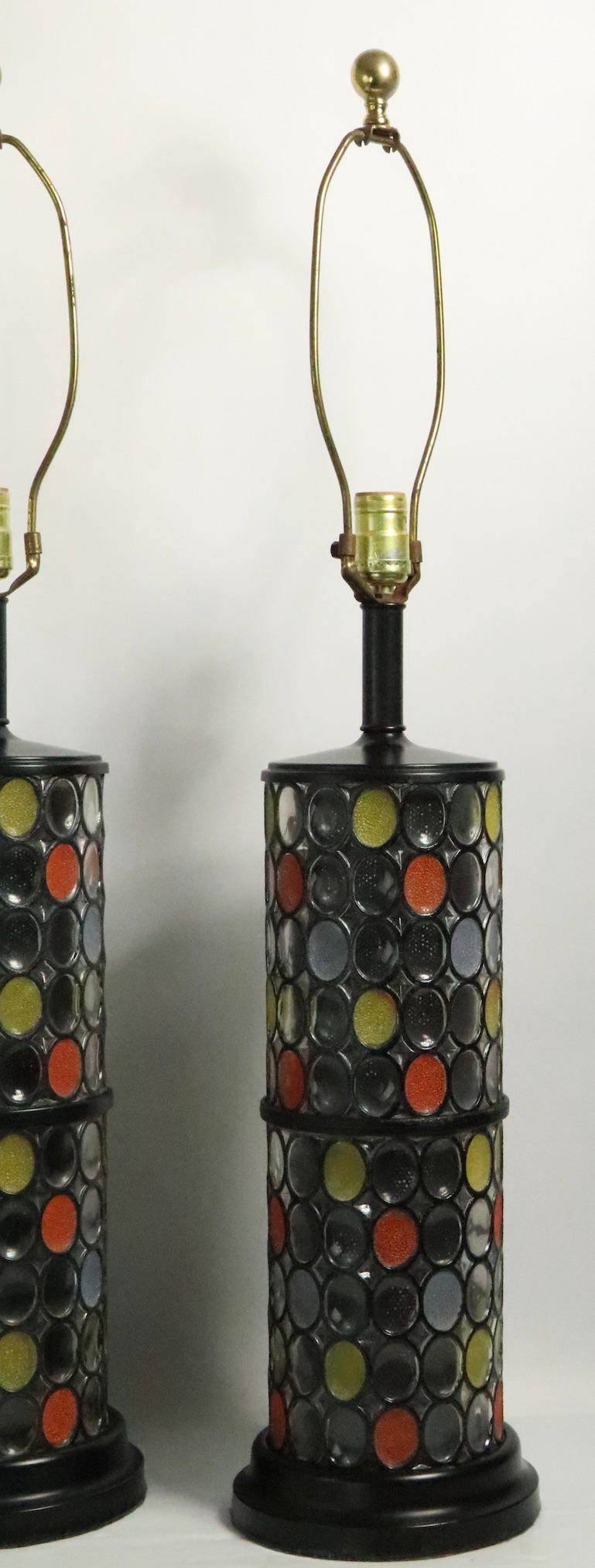 Pair glass table lamps having an oval mosaic style faux leaded surface. The lamps have a perforated cylindrical metal mesh interior, both are in good, clean and working condition. Lamps accept standard size screw in bulbs, shades not