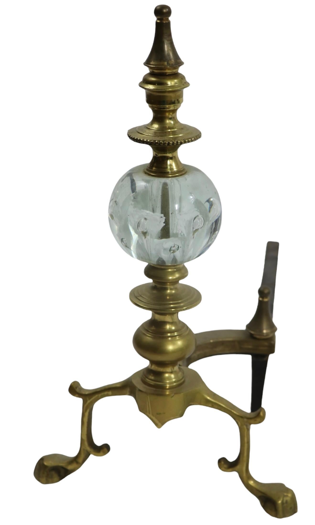 Exceptional pair of andirons by noted and sought after maker, St. Clair. The andirons feature a stunning art glass paperweight ball with interior white flowers, mounted on solid brass stems, and feet. The pair is in very fine, original, clean and