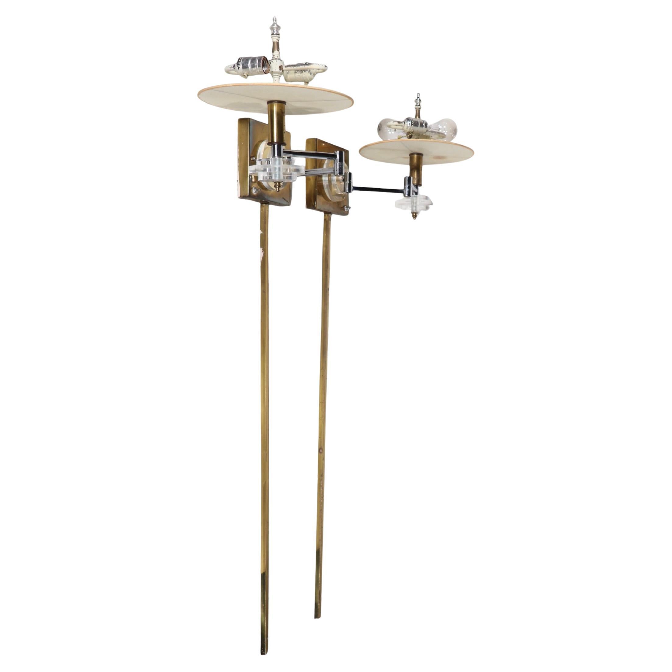 Pair of glamorous Hollywood Regency style brass chrome and lucite flew arm sconces, attributed to Frederick Cooper, circa 1970's. The sconces feature a brass and chrome structure, with thick cast lucite disks as decorative elements. 
 Both sconces