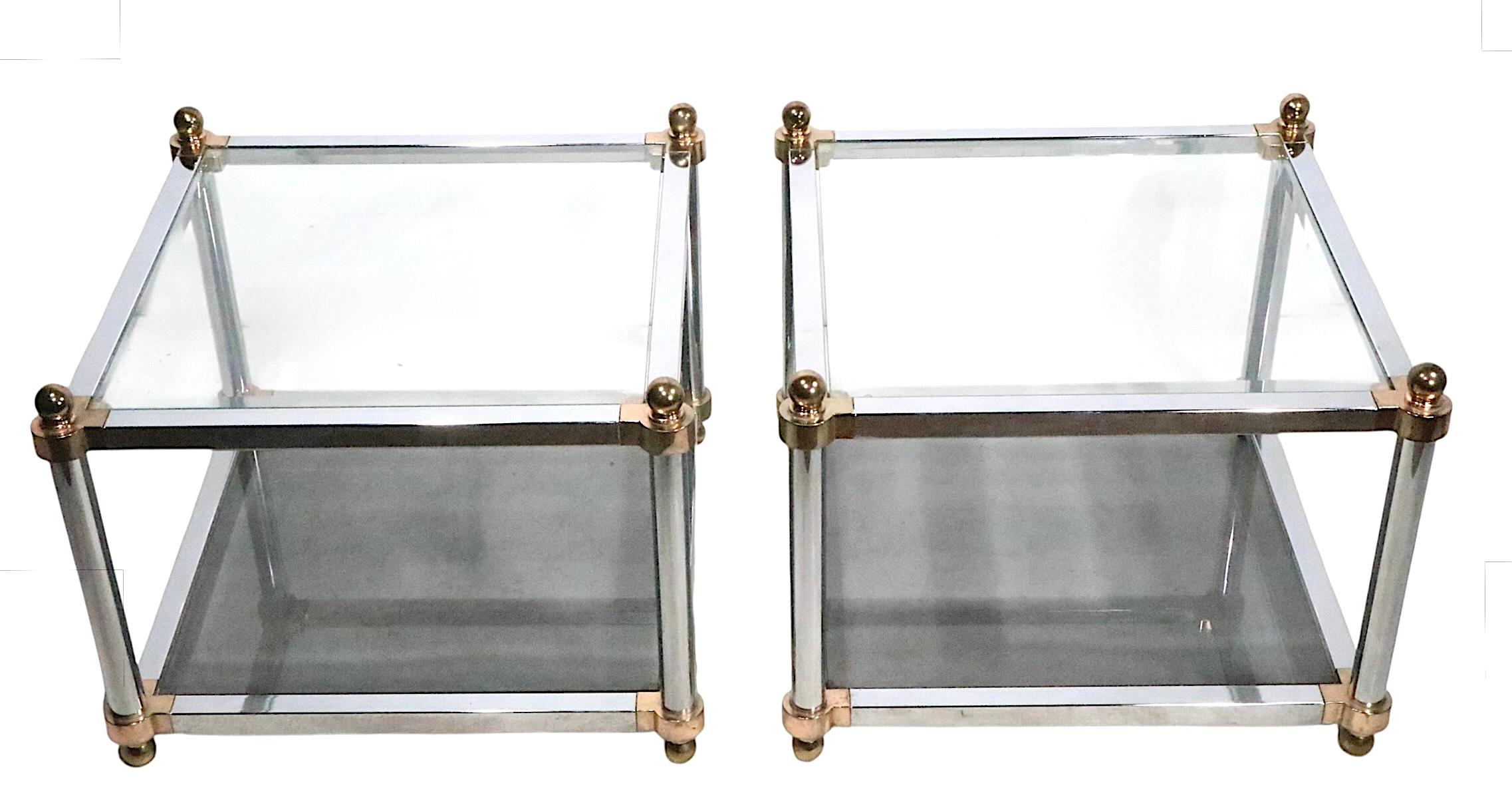 Exceptionnelle paire de tables d'appoint de style Hollywood Regency, avec des cadres chromés et des étagères en verre biseauté. Le plateau supérieur est transparent, le plateau inférieur est en verre teinté. Vers les années 1970, probablement