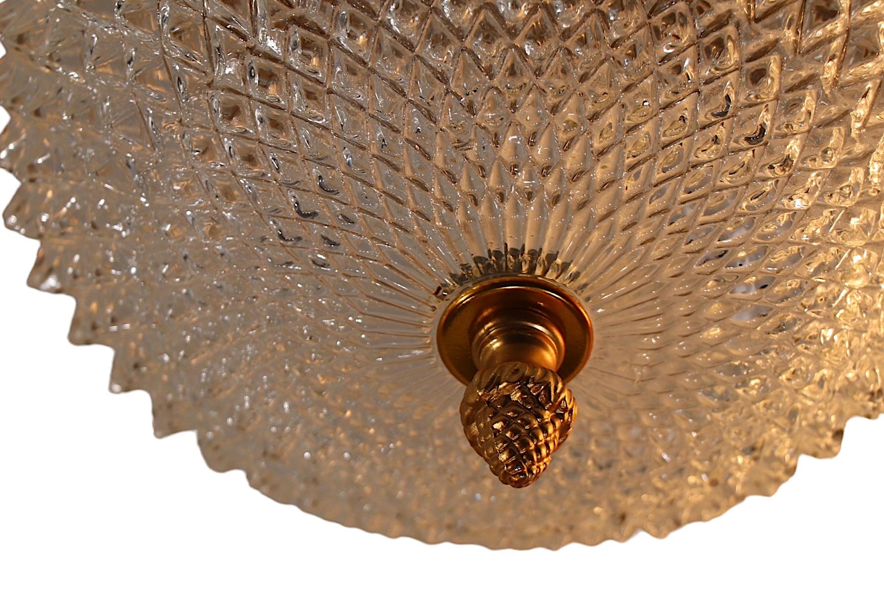 Voguish  paire de suspensions de forme sphérique  globes en verre avec des éléments décoratifs en faux métal doré. Le verre  Les globes ont une surface en dents de scie, chacun ayant un fleuron de couleur laiton et un sommet en métal en forme de