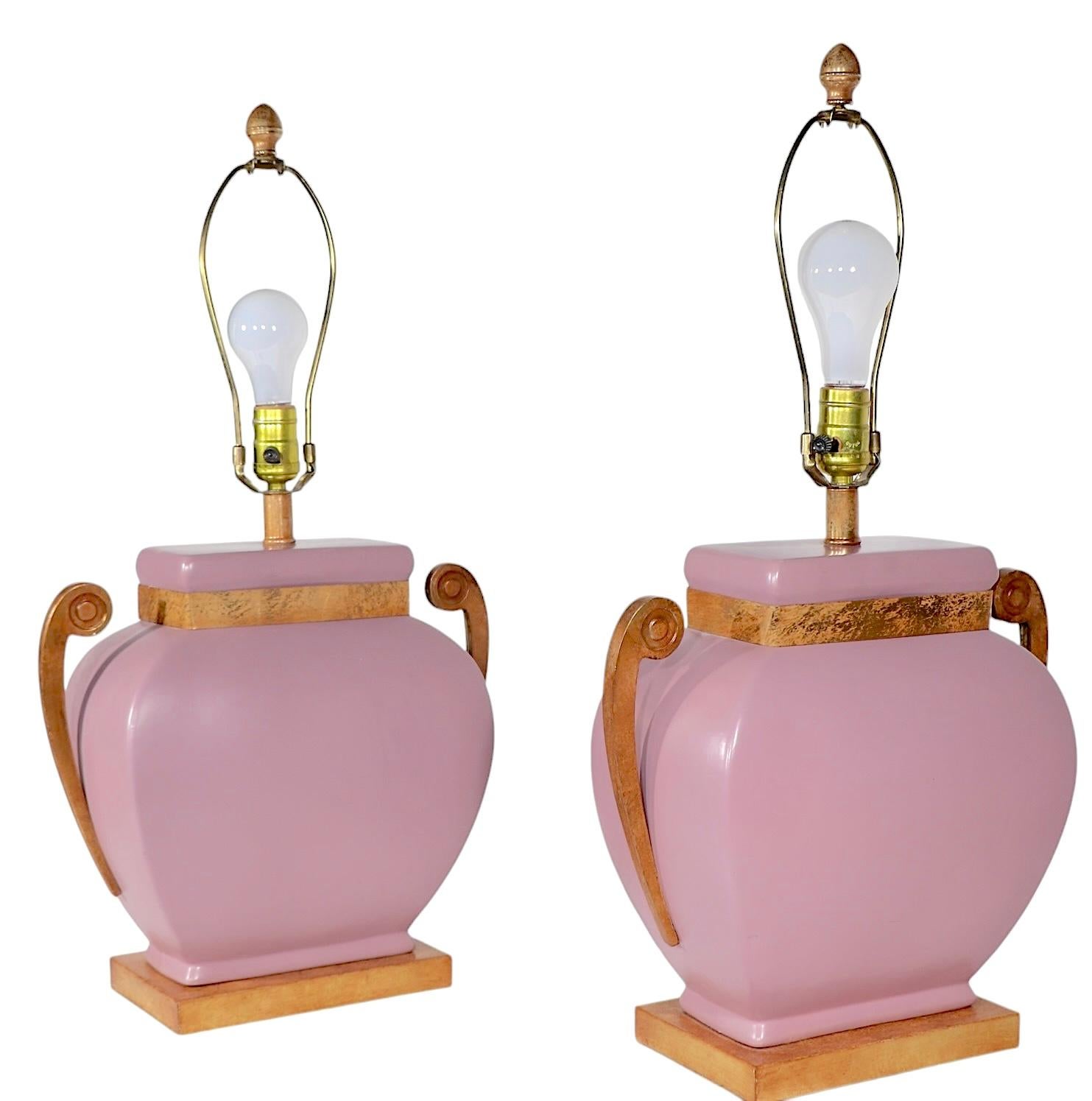 Exceptionnelle paire de lampes de table Hollywood Regency, fabriquées aux Etats-Unis, vers les années 1980. Les lampes présentent des corps en céramique mauve émaillée, avec des bras en forme de poignée en métal faux laiton, sur des socles en bois