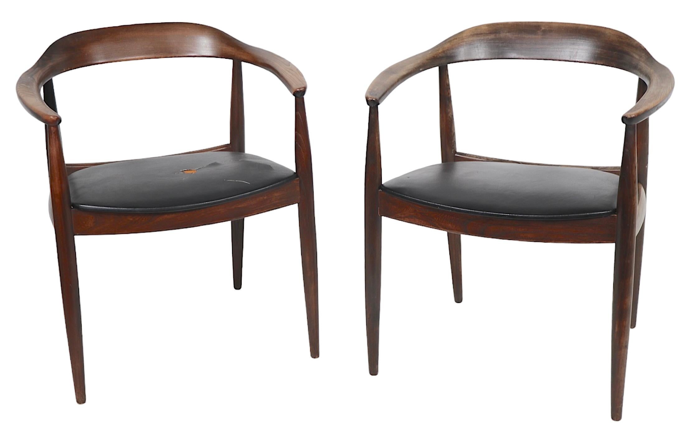 Pair of Danish Mid Century Modern arm, or dining chairs designed by Illum Wikkelso, cabinetry by Niels Eilersen, made in Denmark circa 1950's. These classic chairs are constructed of solid wood, I believe they are teak, with vinyl seats.
 The chairs