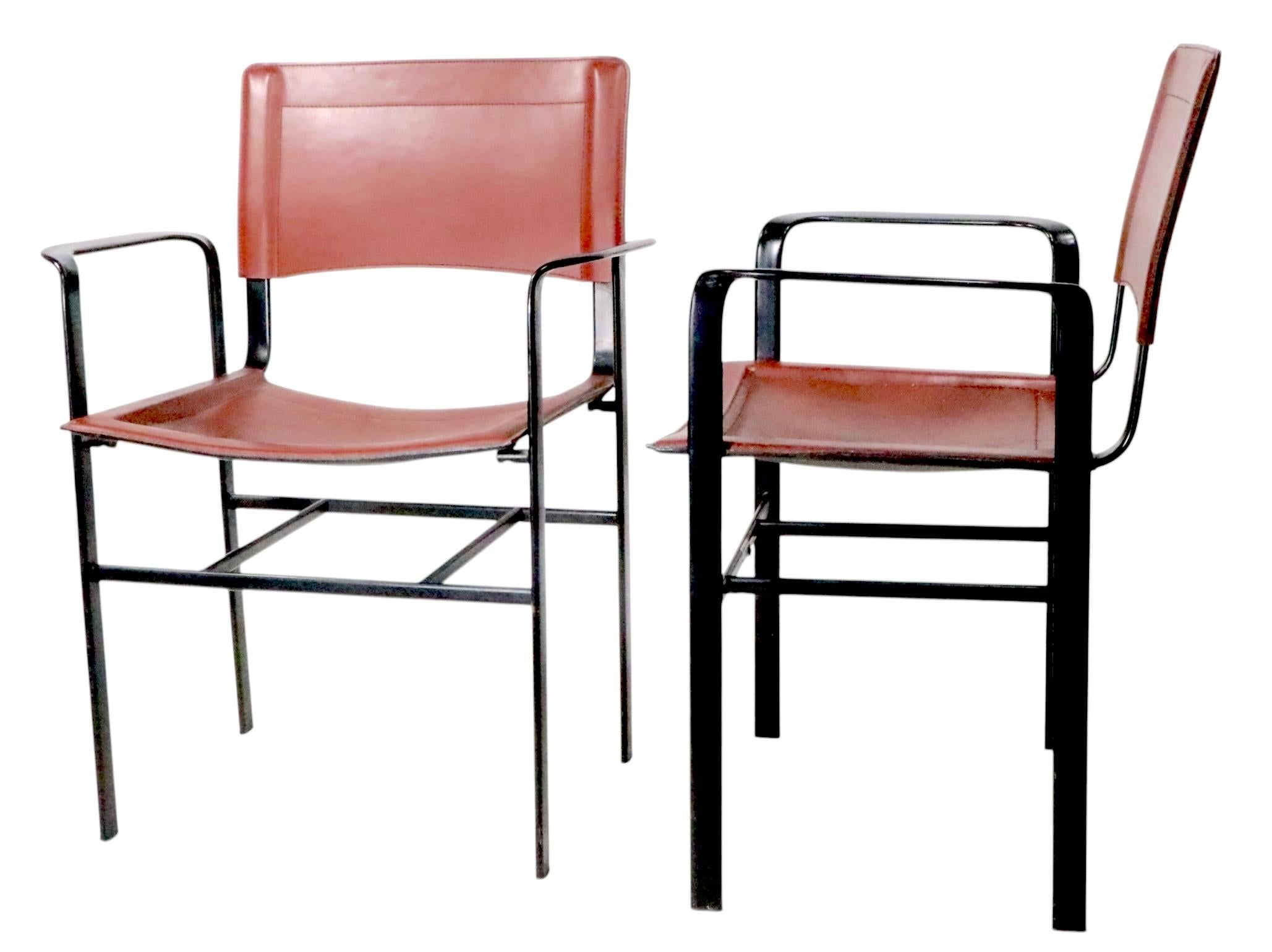 Paire chic de fauteuils post-modernes de conception architecturale fabriqués en Italie par Cidue, vers les années 1970. Les chaises sont dotées d'une  assise et dossier en cuir marron, et cadres en acier noir émaillé. Les deux sont en bon état,