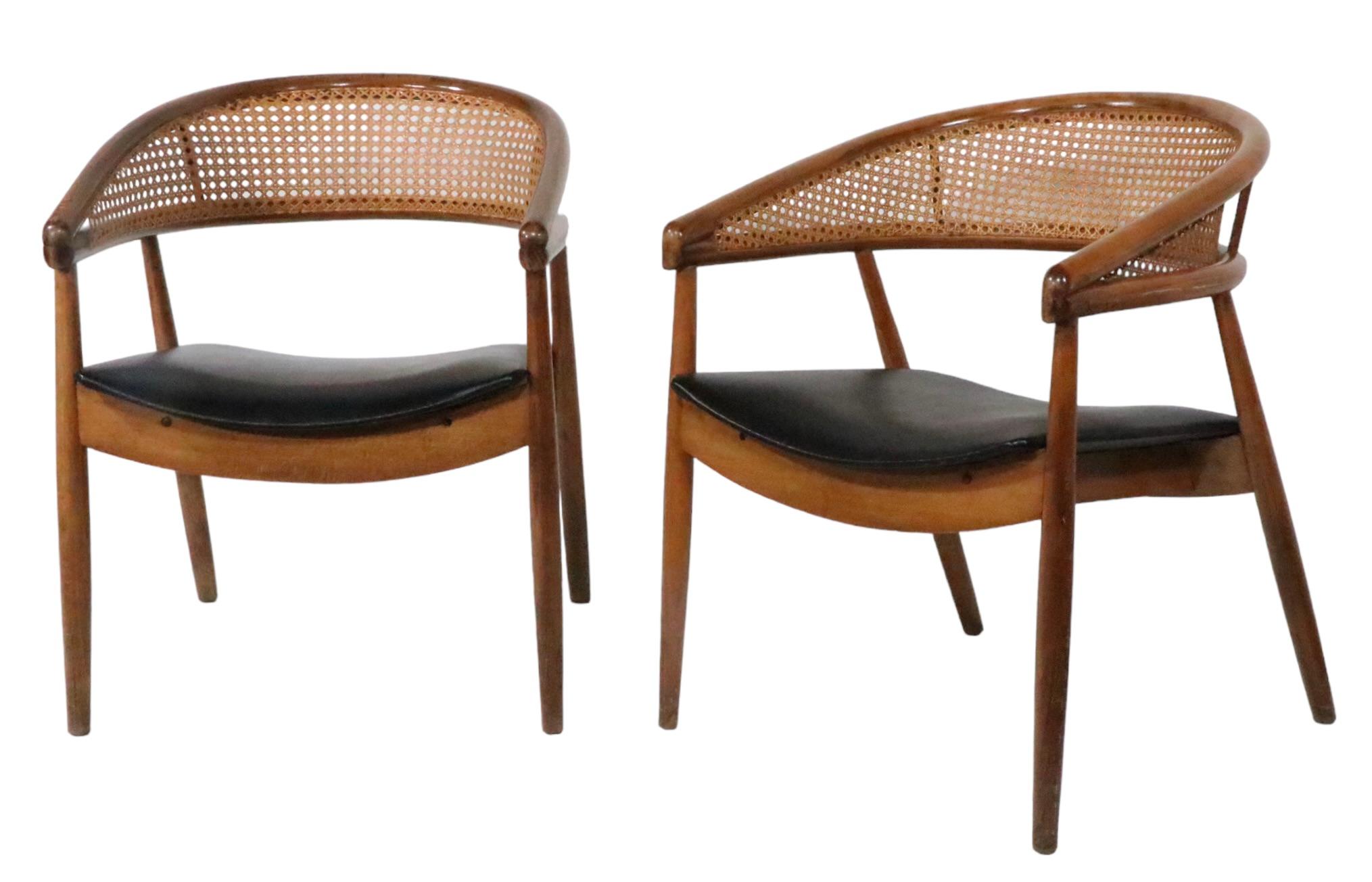 Chic, sleek, and  sophisticated pair of caned back lounge chairs, known as the King Cole chair, design attributed to James mont. The chairs feature a dramatic scoop form backrest, constructed of bentwood and canning, upholstered seat cushions, and