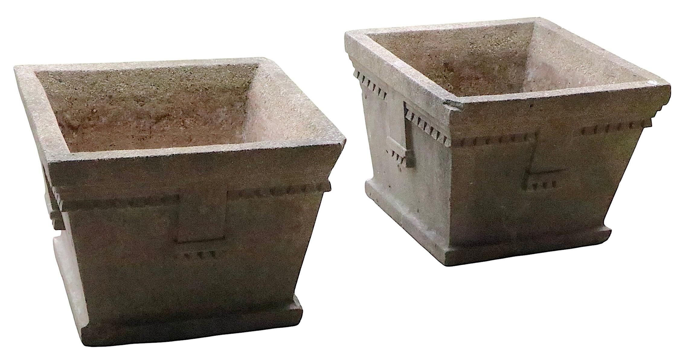 Spectacular pair of Art Deco cement planters made in the USA circa 1930's. 
 The planters feature stylized  geometric trim in deep relief, having square bodies, with tapering wall sides. Both are structurally sound and sturdy, both show minor flaws