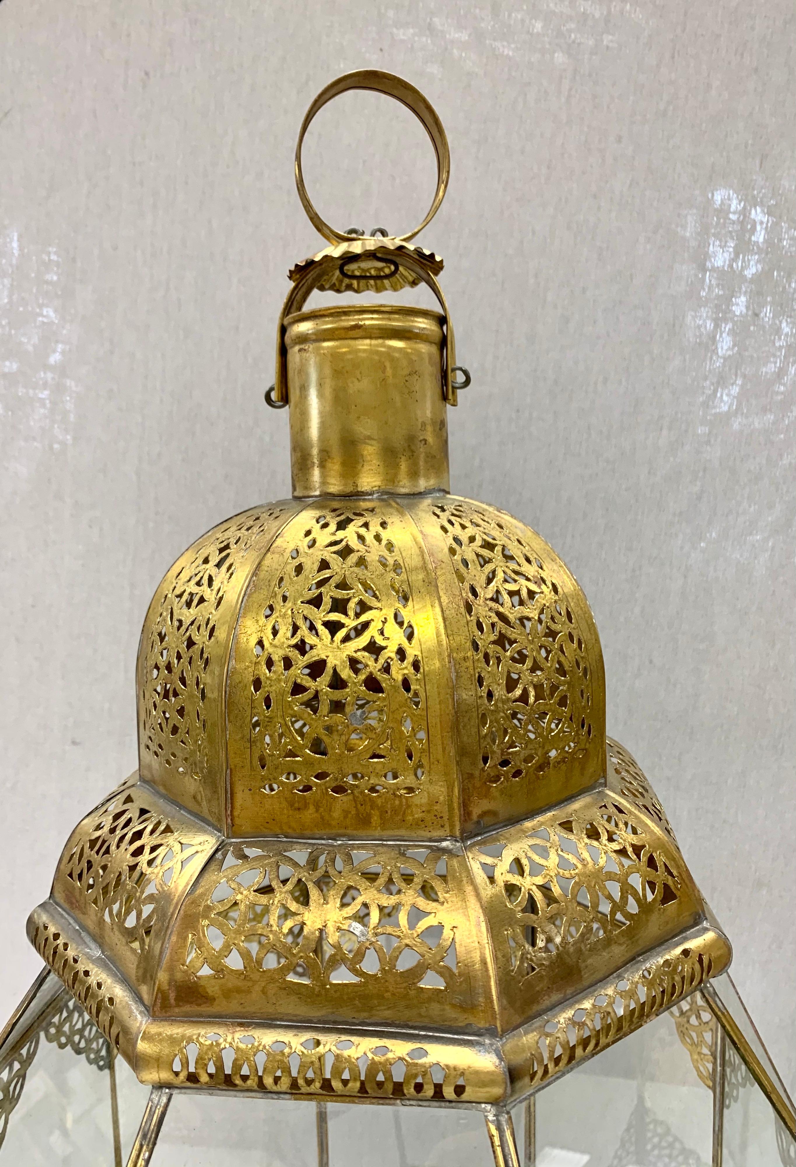 Exquisite Moorish brass and glass lanterns with beautiful intricate brass filigree have eight sides with one side having a door to access the inside. Handcrafted in Morocco in the 1990s. They can be used hanging from the ceiling, or sitting on a
