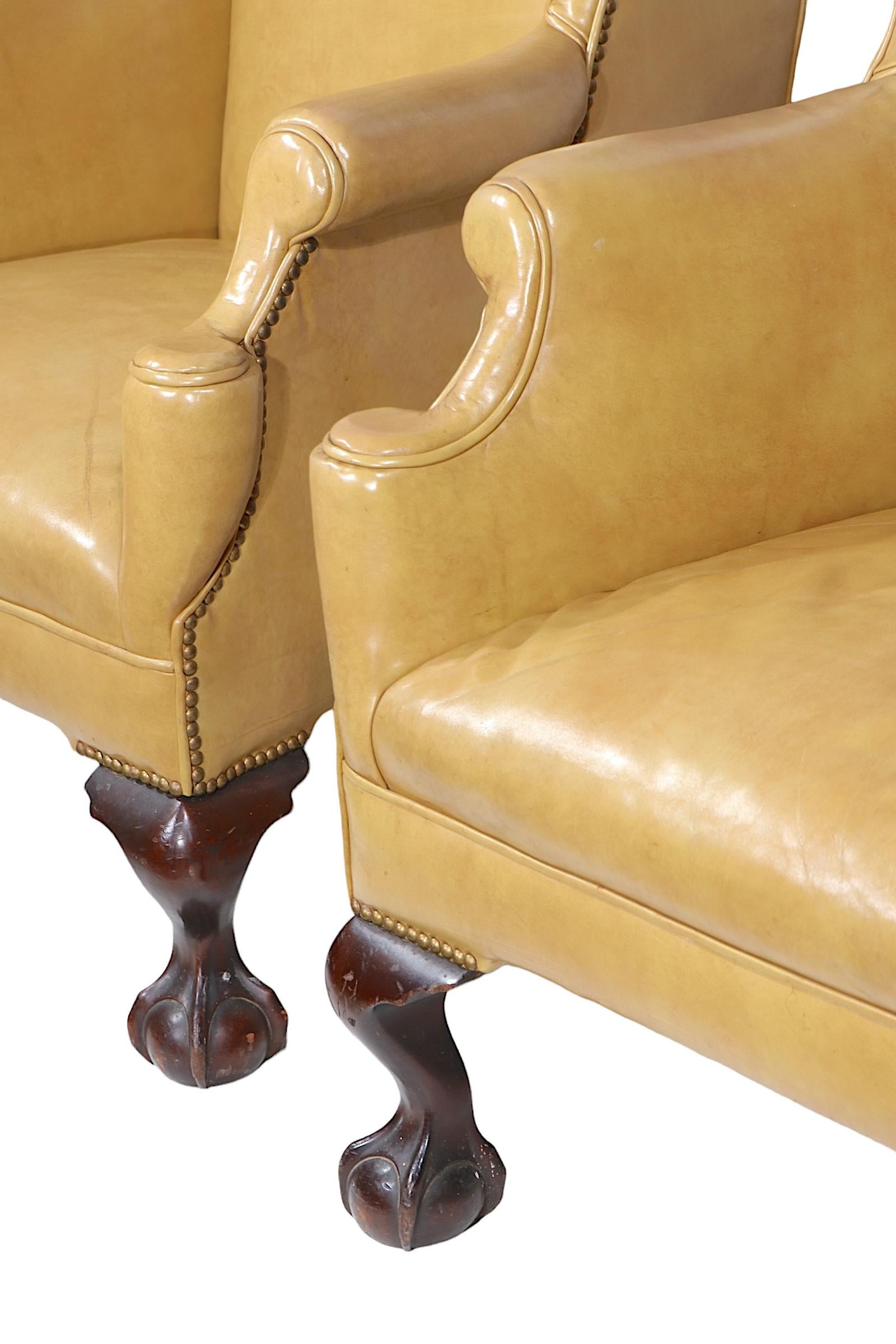Exceptional pair of wing back chairs, originally from the historic Fort William Henry Hotel, in Lake George NY. The chairs have leather upholstery with decorative nailhead studs, with gutsy ball and claw feet. The chairs are very well crafted,